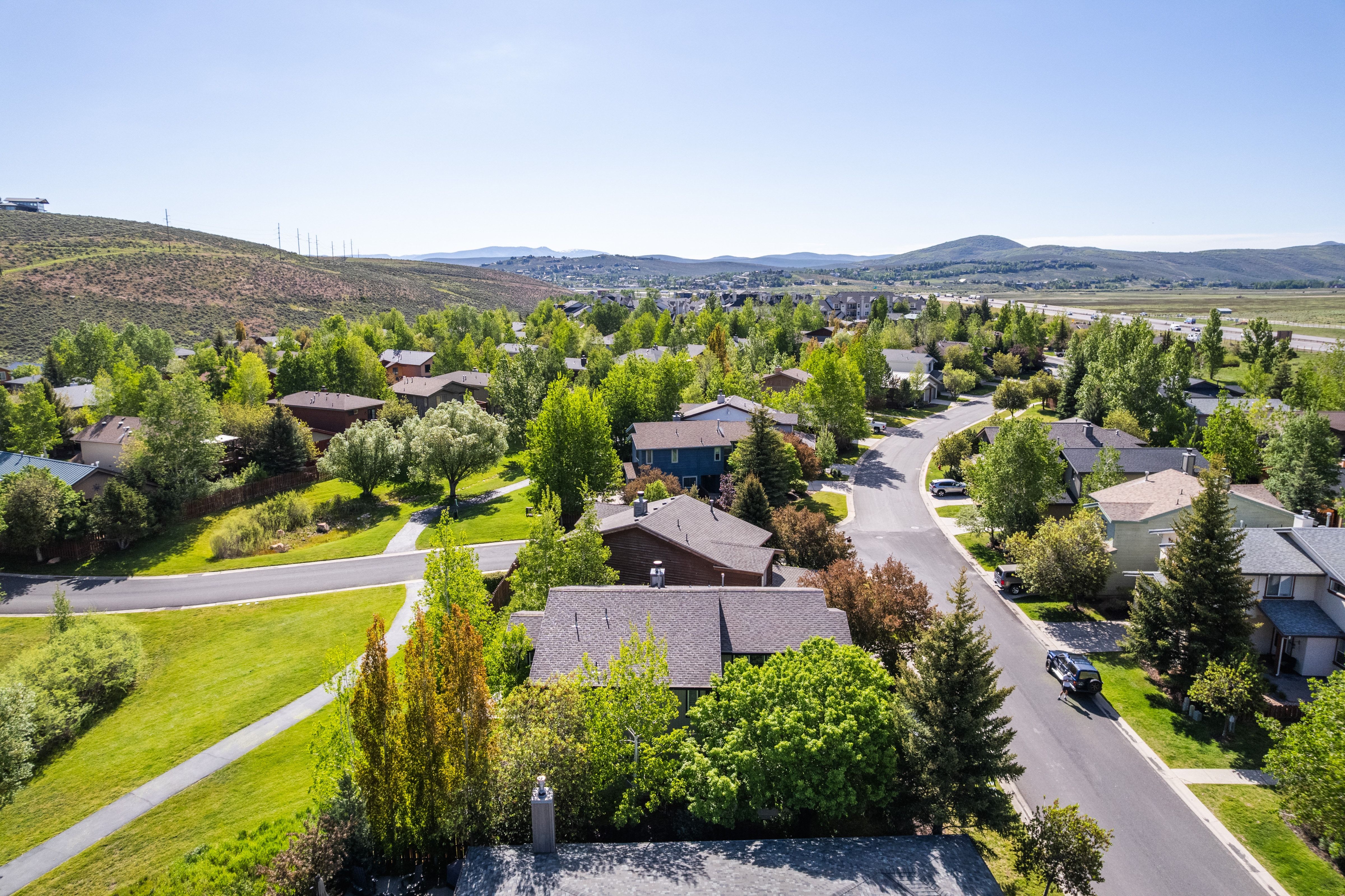 Aerial perspective showcasing a residential area with varied home exteriors, mature trees, and paved roads