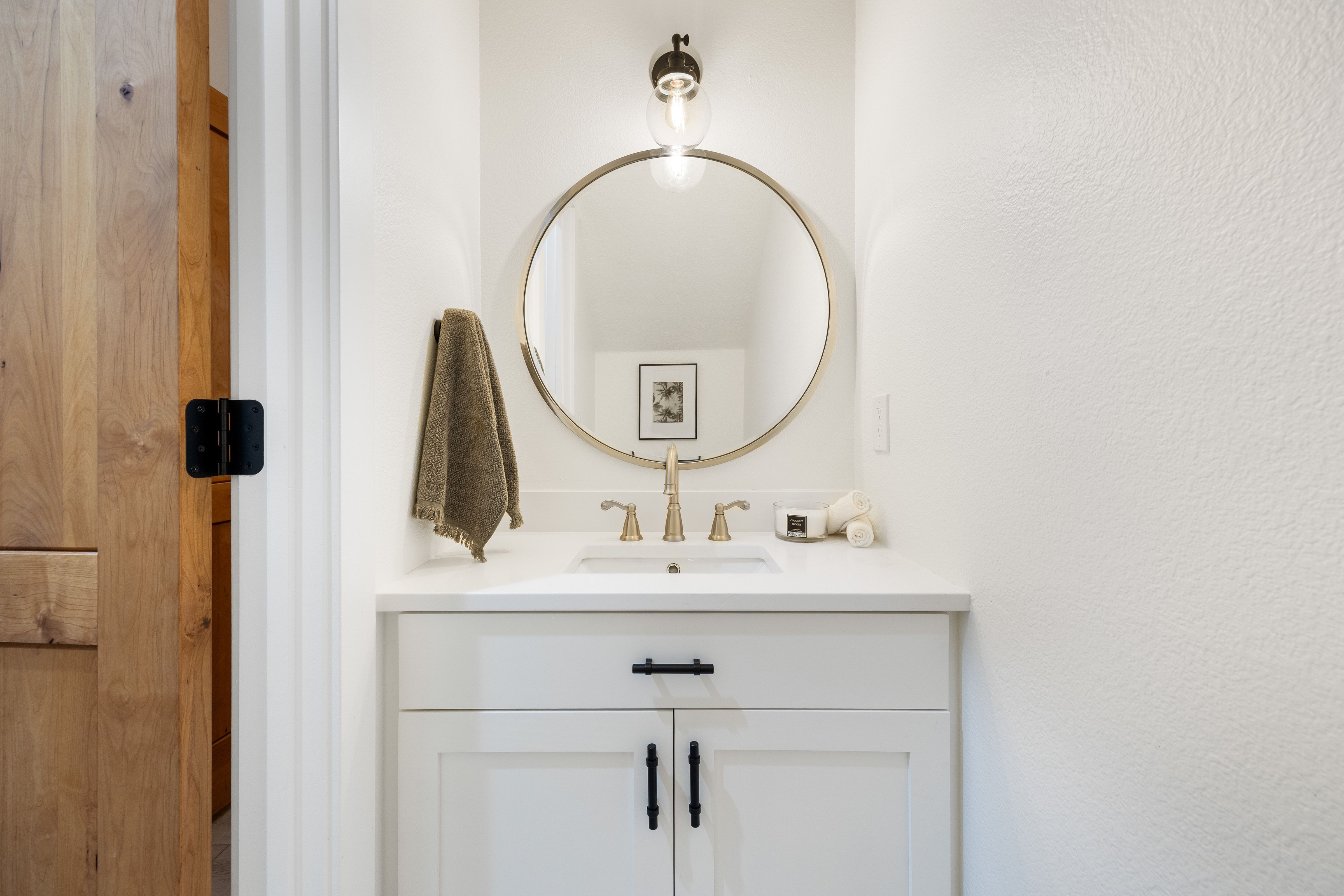 Vanity area featuring a white cabinet with shaker-style doors, black hardware, a light-colored countertop, and an undermount sink