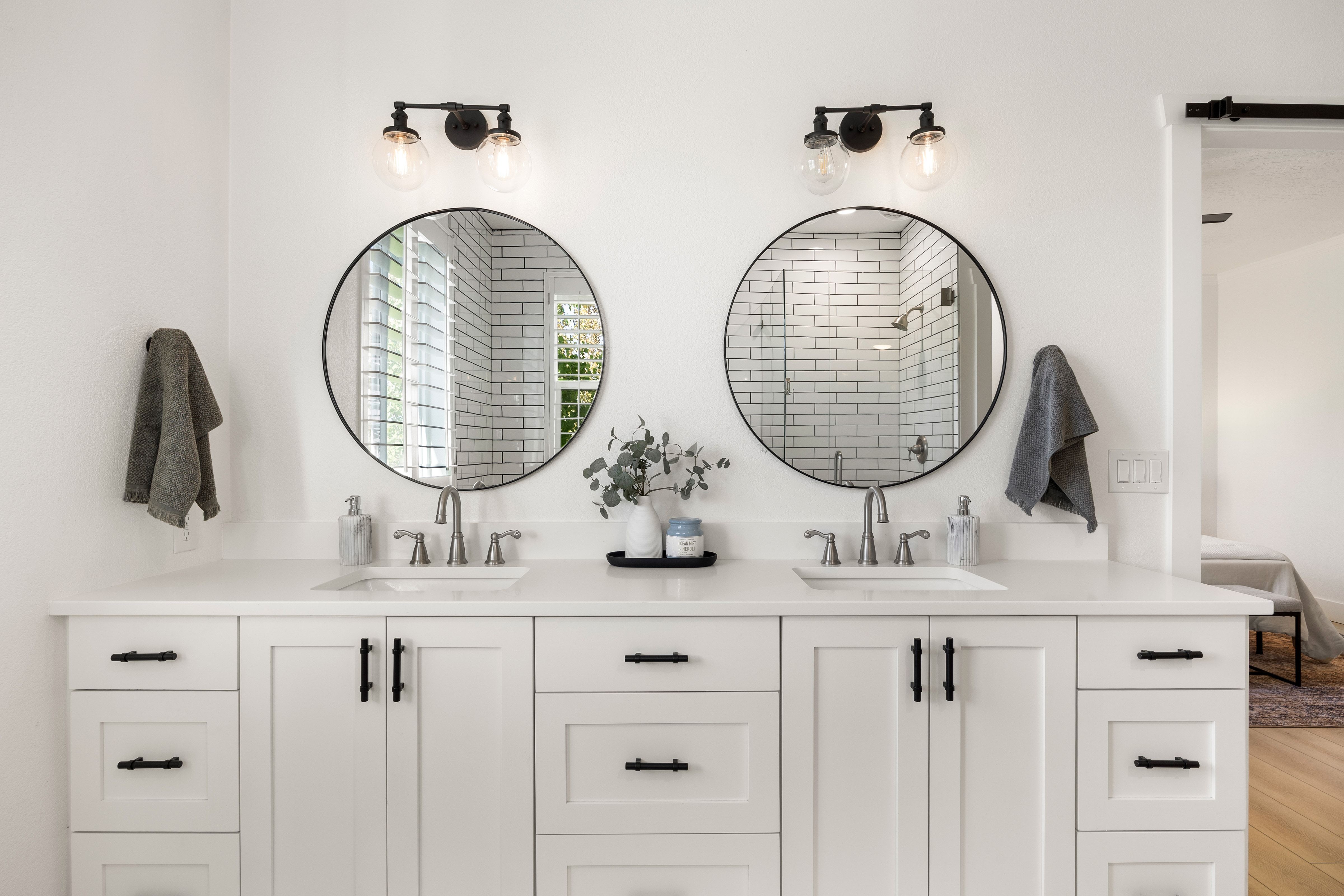 Dual vanity with white shaker cabinetry and black hardware