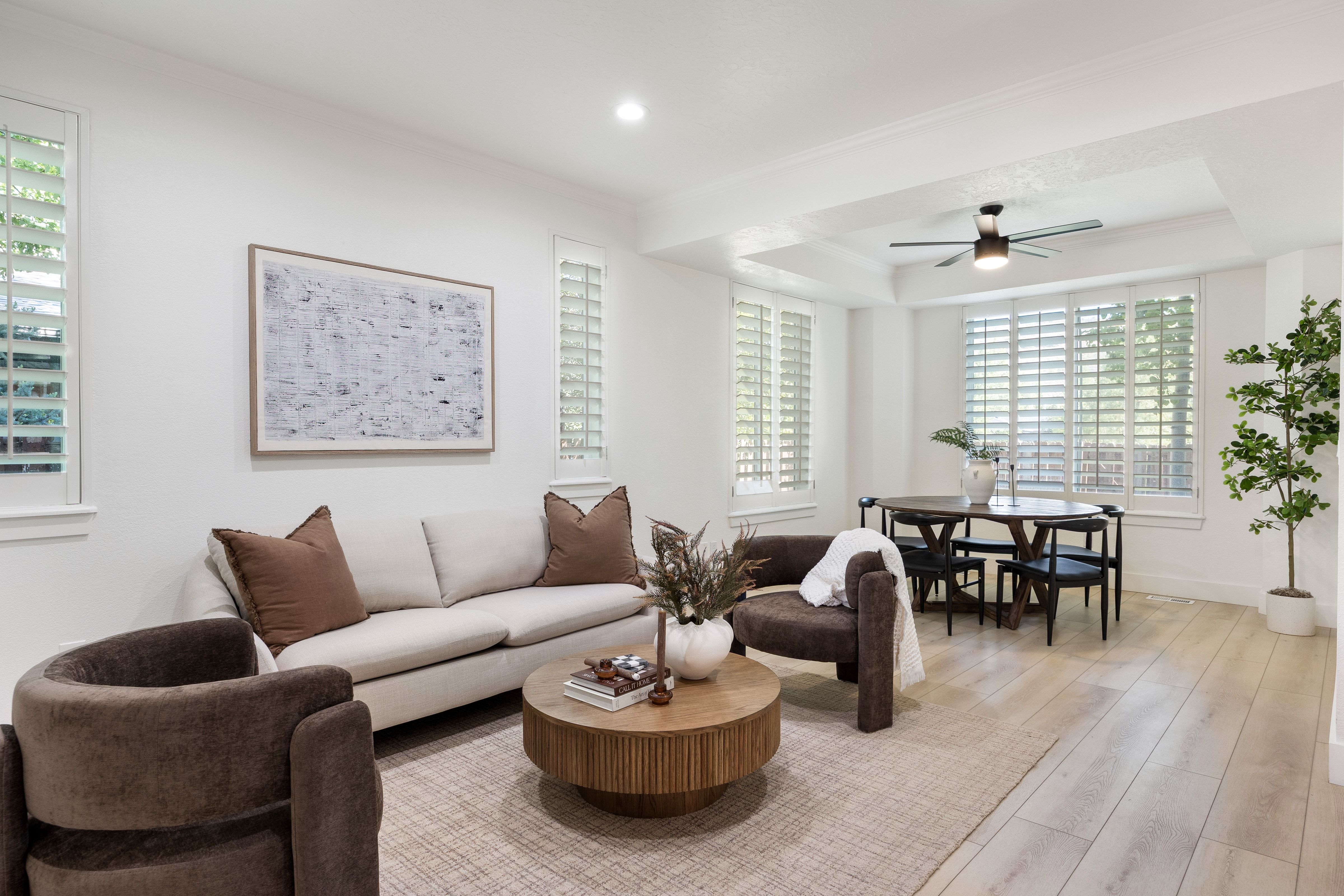 Open-concept living space featuring light wood-finish flooring, white walls, and a tray ceiling in the dining area