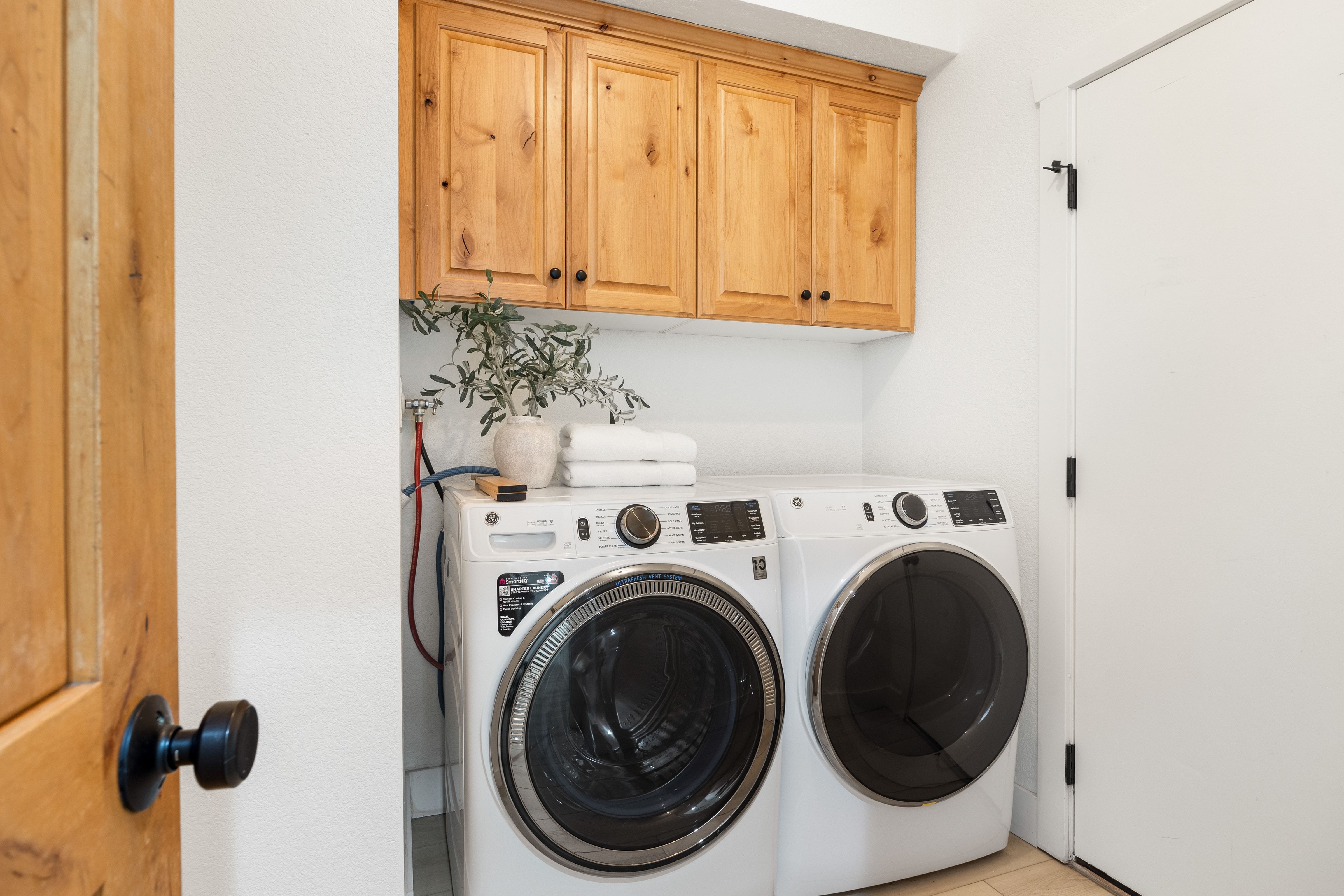 Dedicated laundry area featuring wood cabinetry, a light-toned door with a black knob, and a floor-mounted appliance set