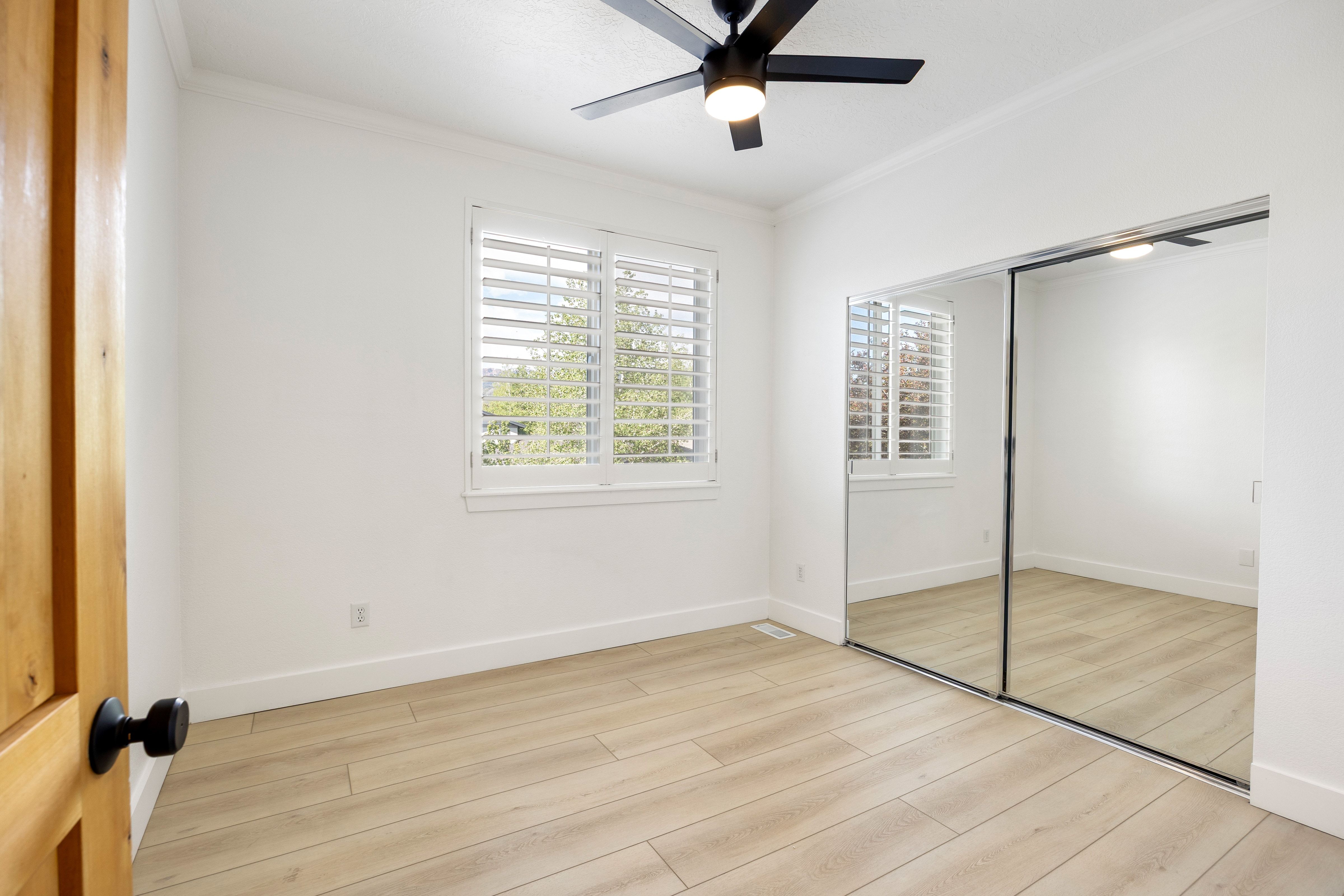 Light-filled interior featuring wood-finish flooring, white walls, and a window with plantation shutters