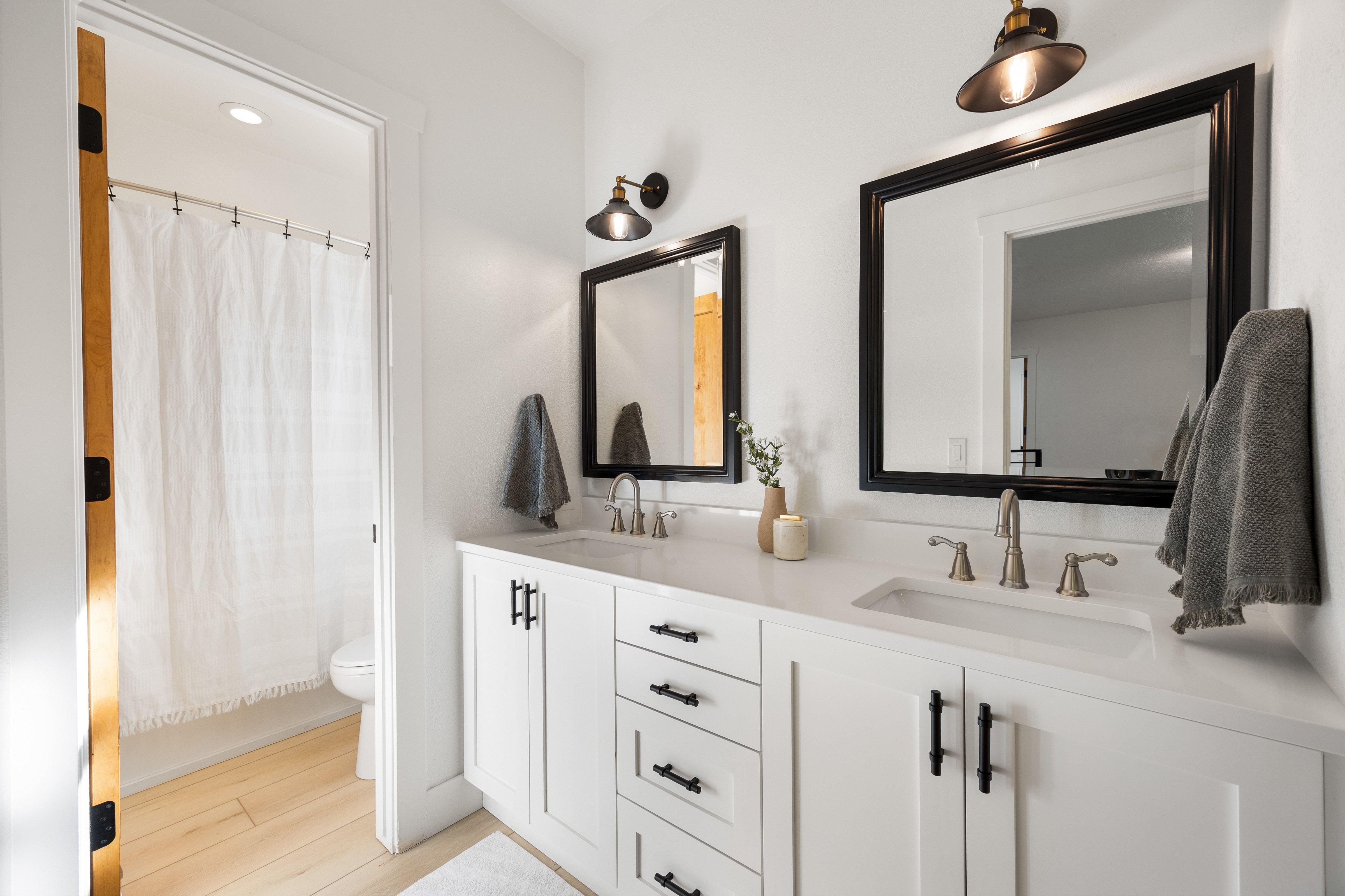 Dual vanity featuring white shaker cabinetry, quartz countertops, and matte black hardware