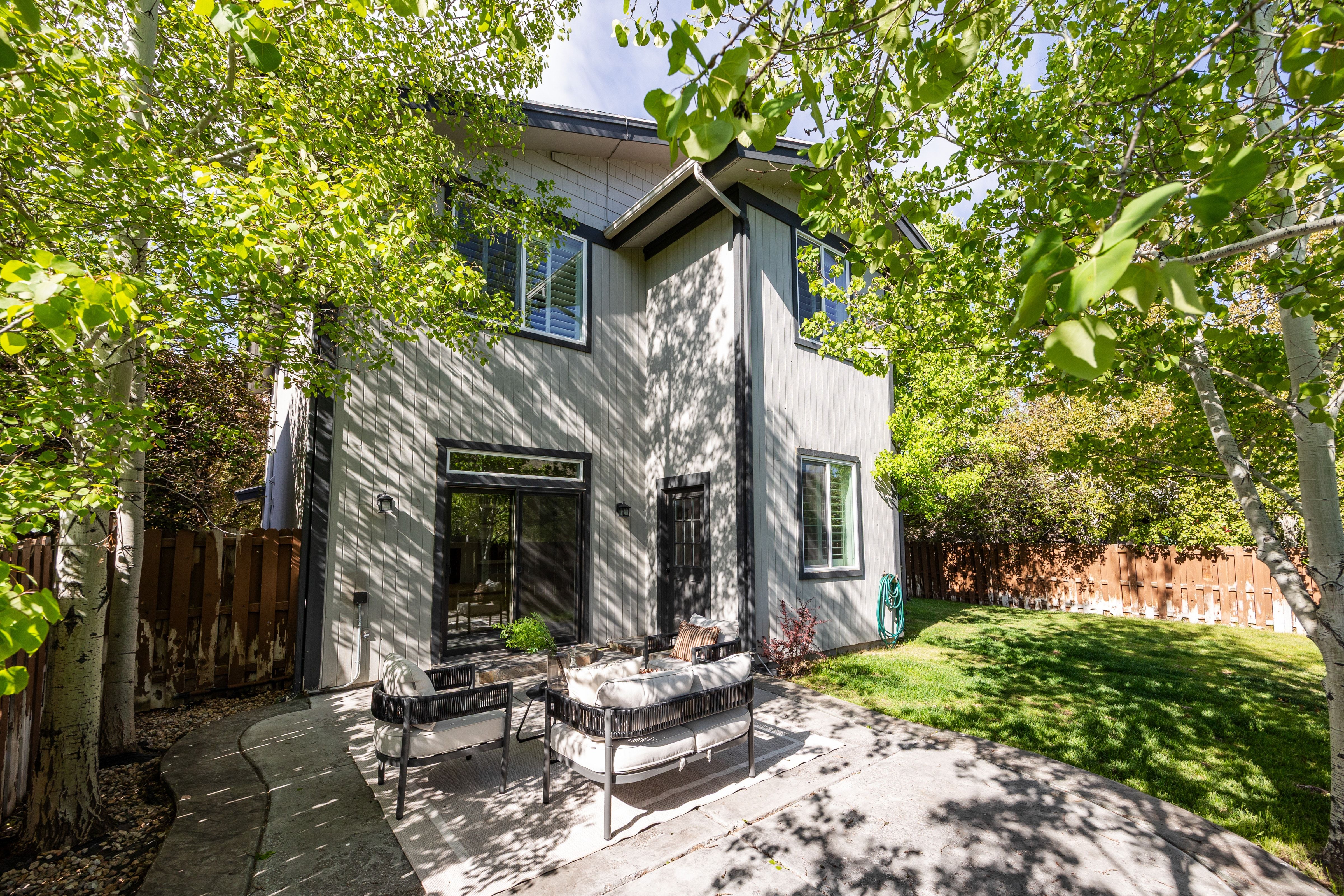 Private backyard featuring a paved patio, manicured lawn, and mature trees