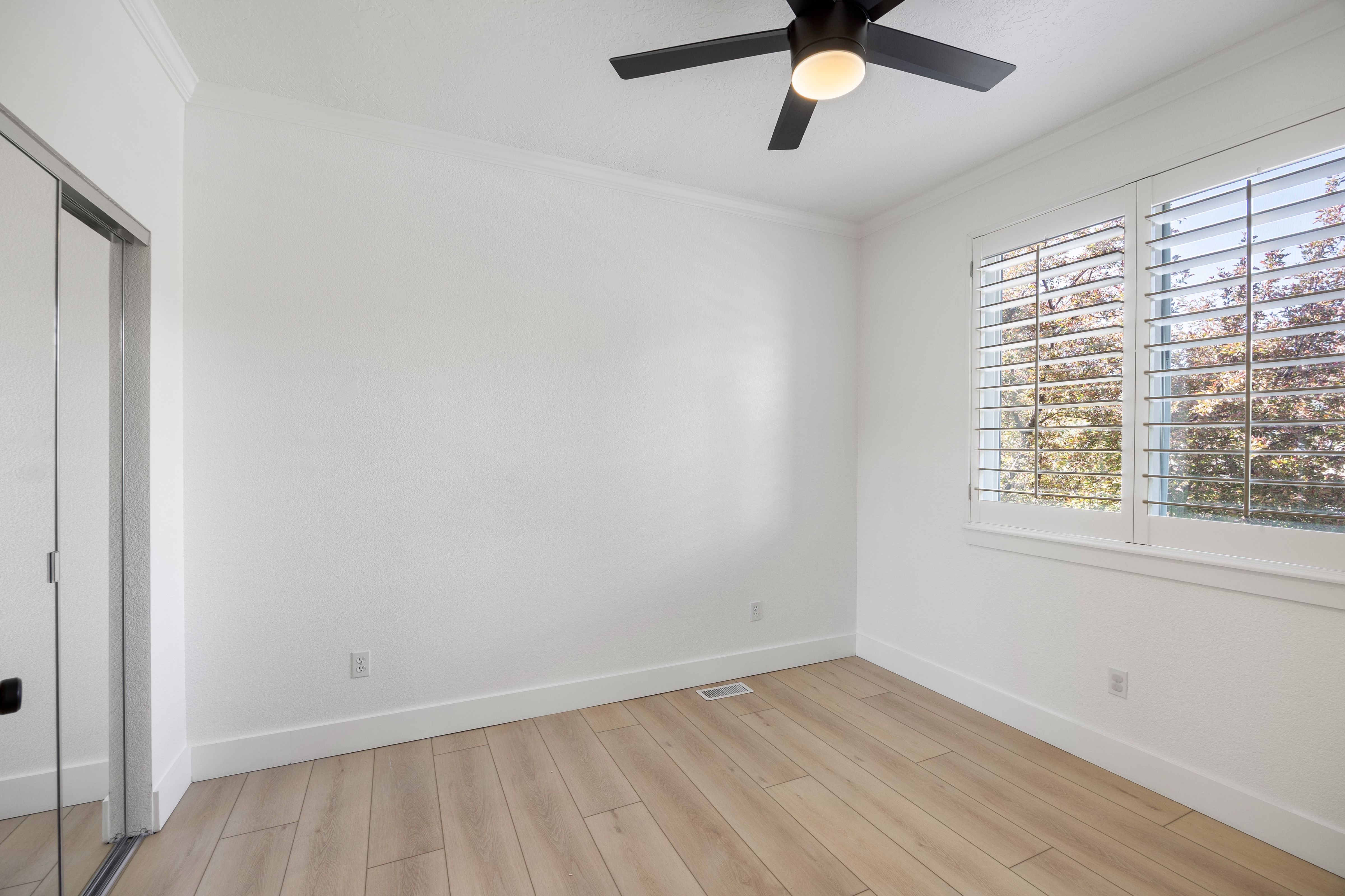 Bright interior space featuring wood-finish flooring, white walls, and crown molding