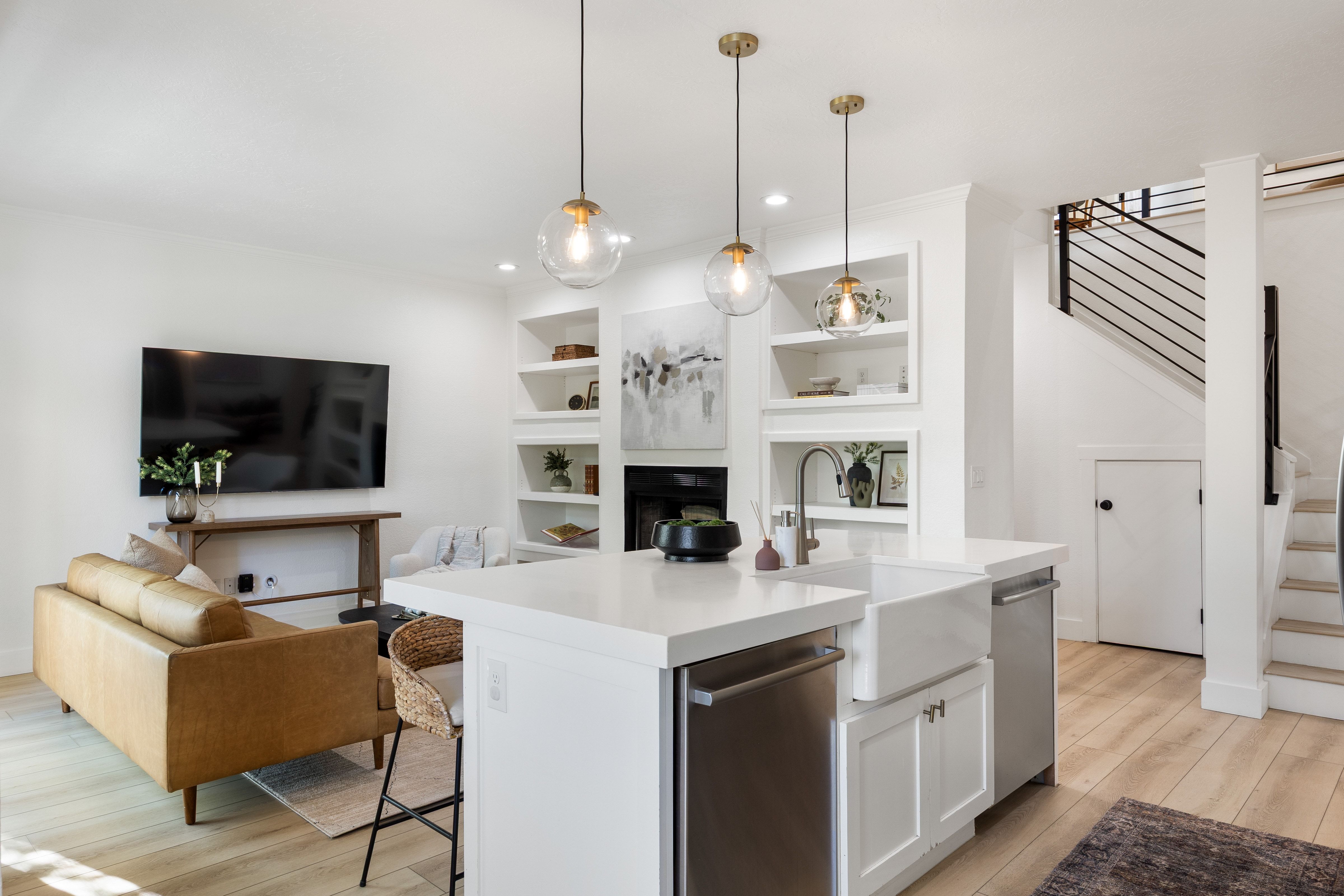 Open-concept living area featuring light wood-finish flooring, white walls, and built-in shelving surrounding a fireplace