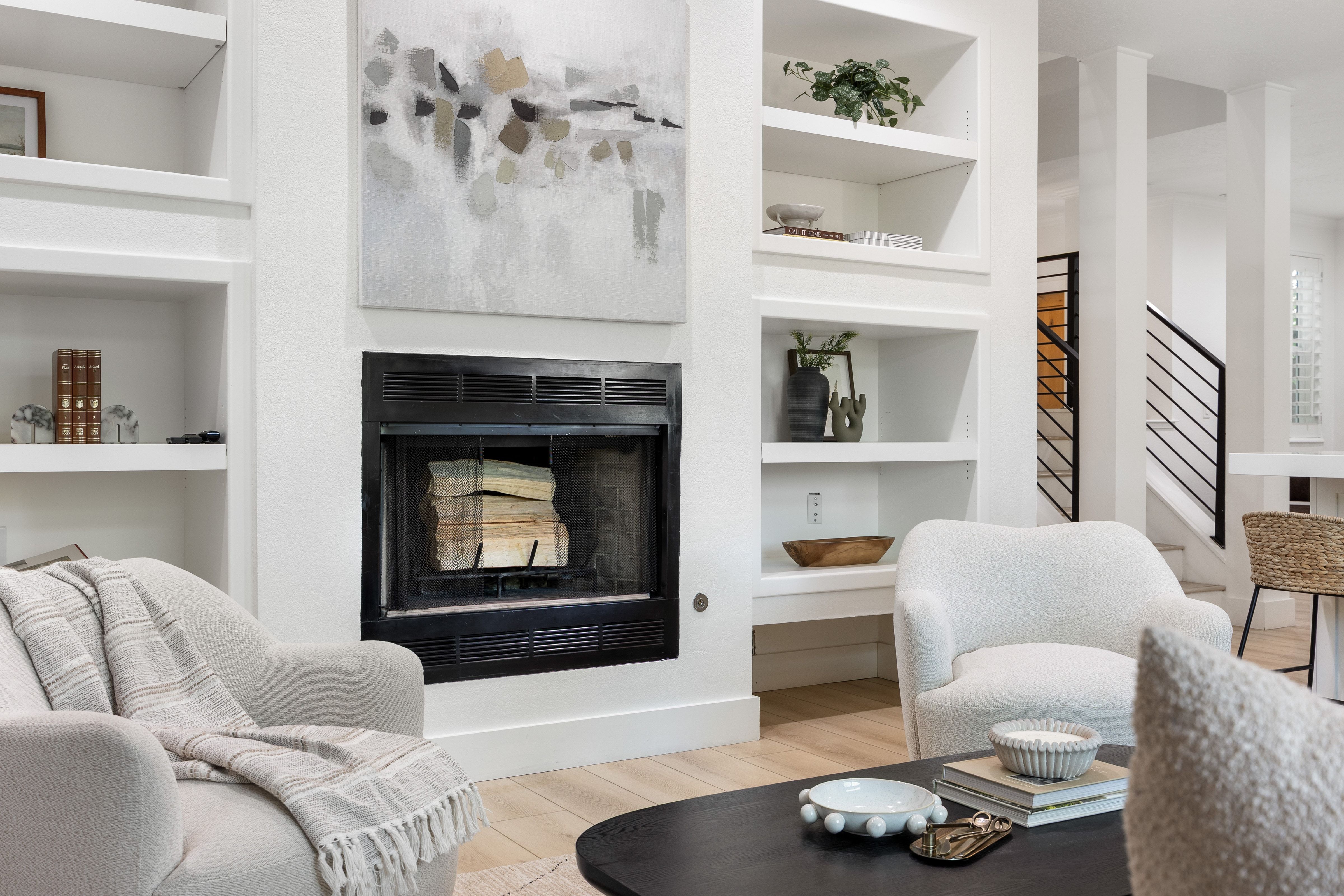 Modern fireplace with a black surround and glass doors, flanked by built-in shelving units