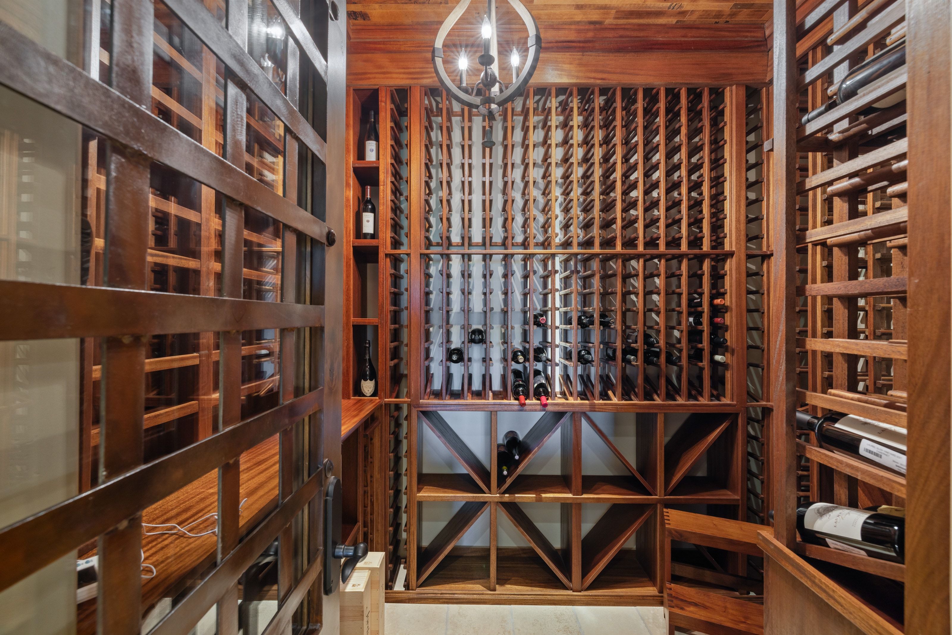 Custom wine cellar featuring extensive wood-finish racking, a built-in display shelf, specialty storage cubbies, a wood-finish ceiling, and a prominent chandelier light fixture