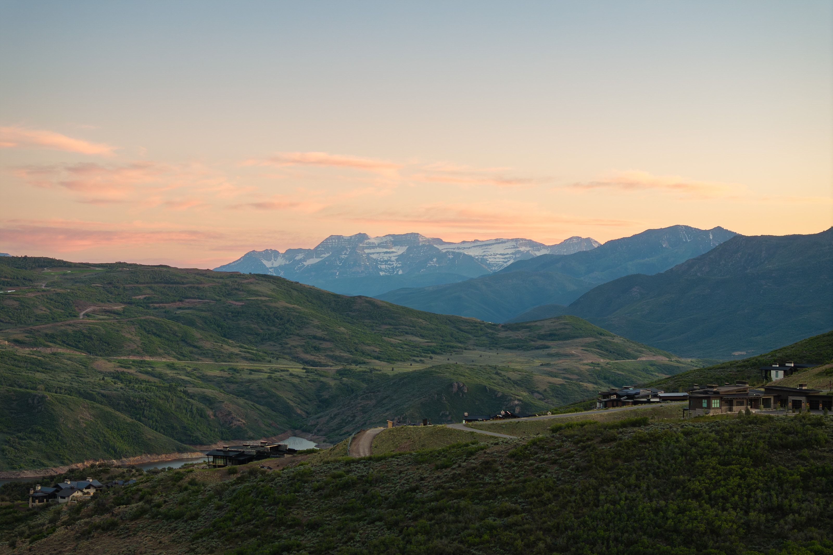 Expansive mountain landscape featuring distant snow-capped peaks and rolling green hills