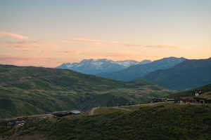 Expansive mountain landscape featuring distant snow-capped peaks and rolling green hills