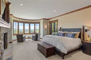Spacious room featuring a stone-clad fireplace, a curved bay window with wood-frame windows, recessed lighting, and crown molding