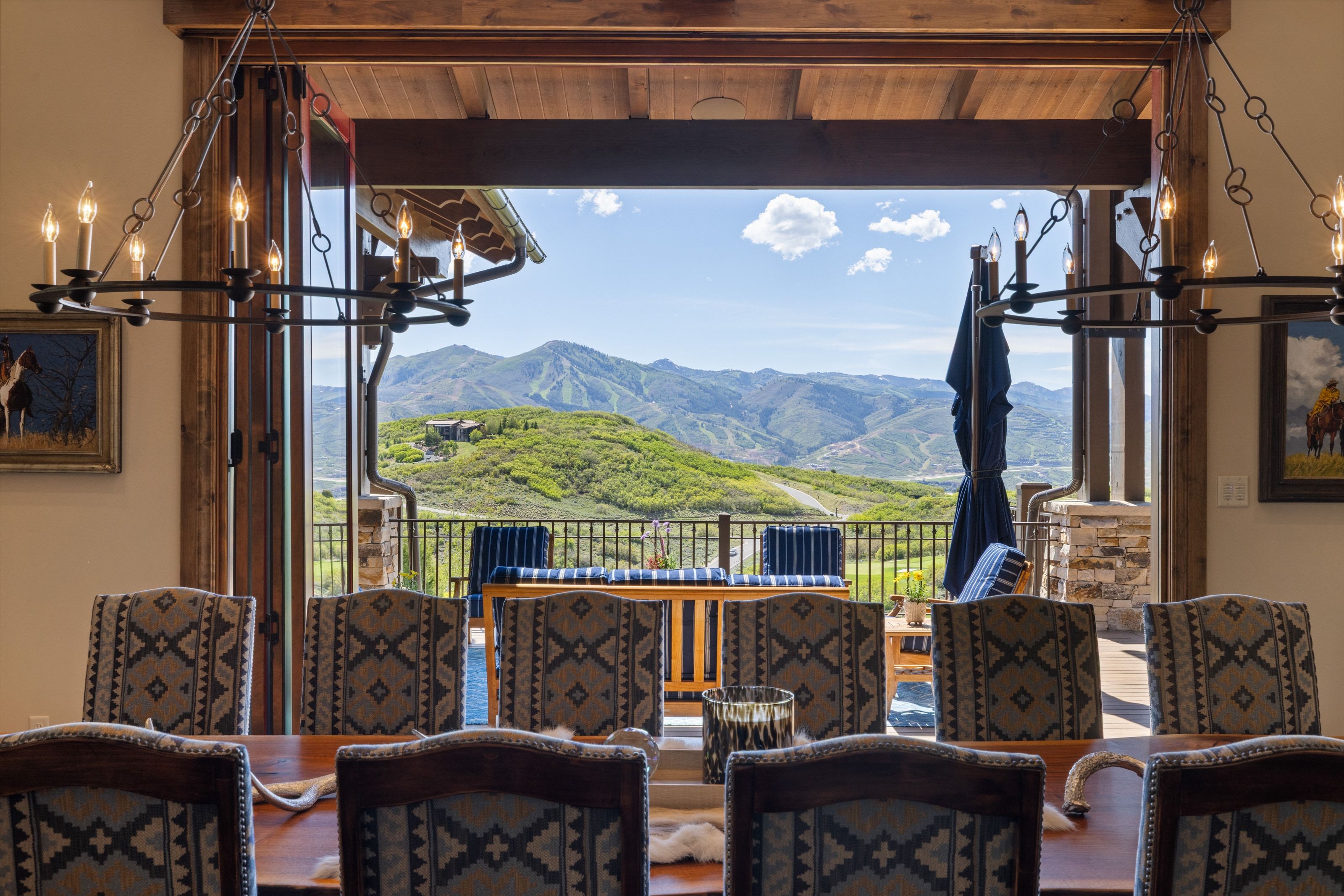 Expansive bi-fold glass doors open to an outdoor patio with mountain scenery