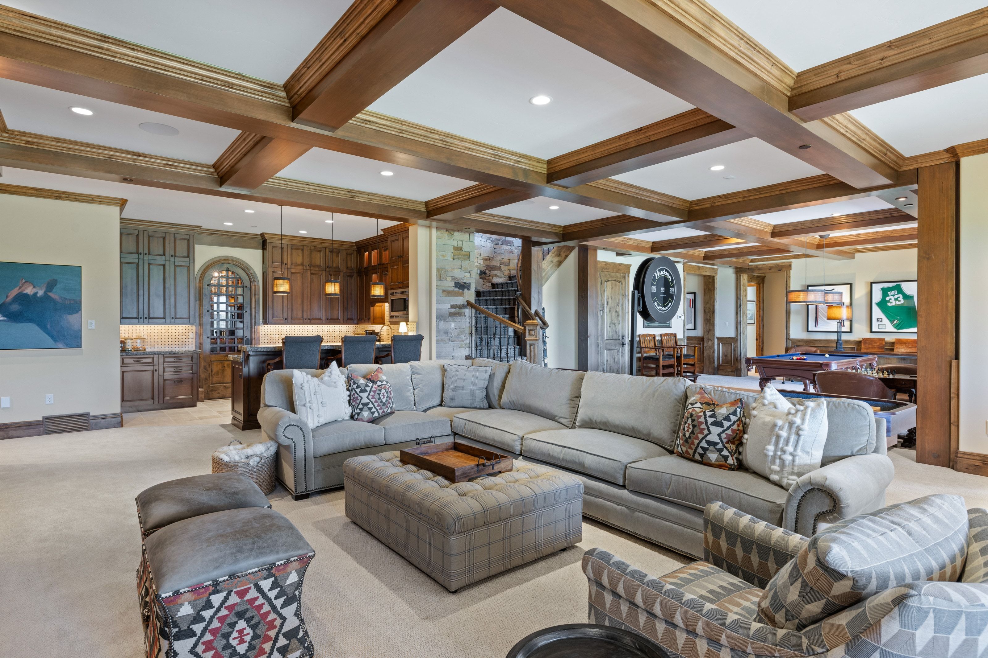Expansive recreation space featuring exposed wood beam ceilings, a built-in wet bar with cabinetry, stone accents, and recessed lighting
