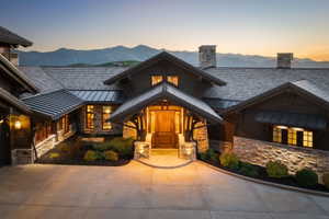 Craftsman-style exterior with stone and wood siding, prominent gabled entry with a solid wood door, concrete driveway, and mature landscaping