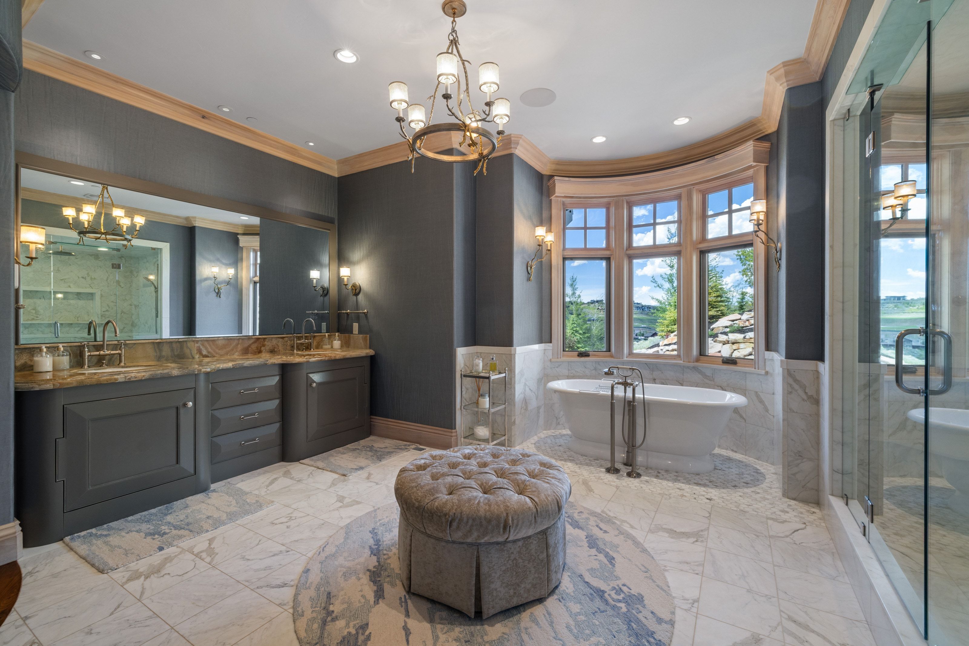 Freestanding soaking tub set against a bay window with a stone surround