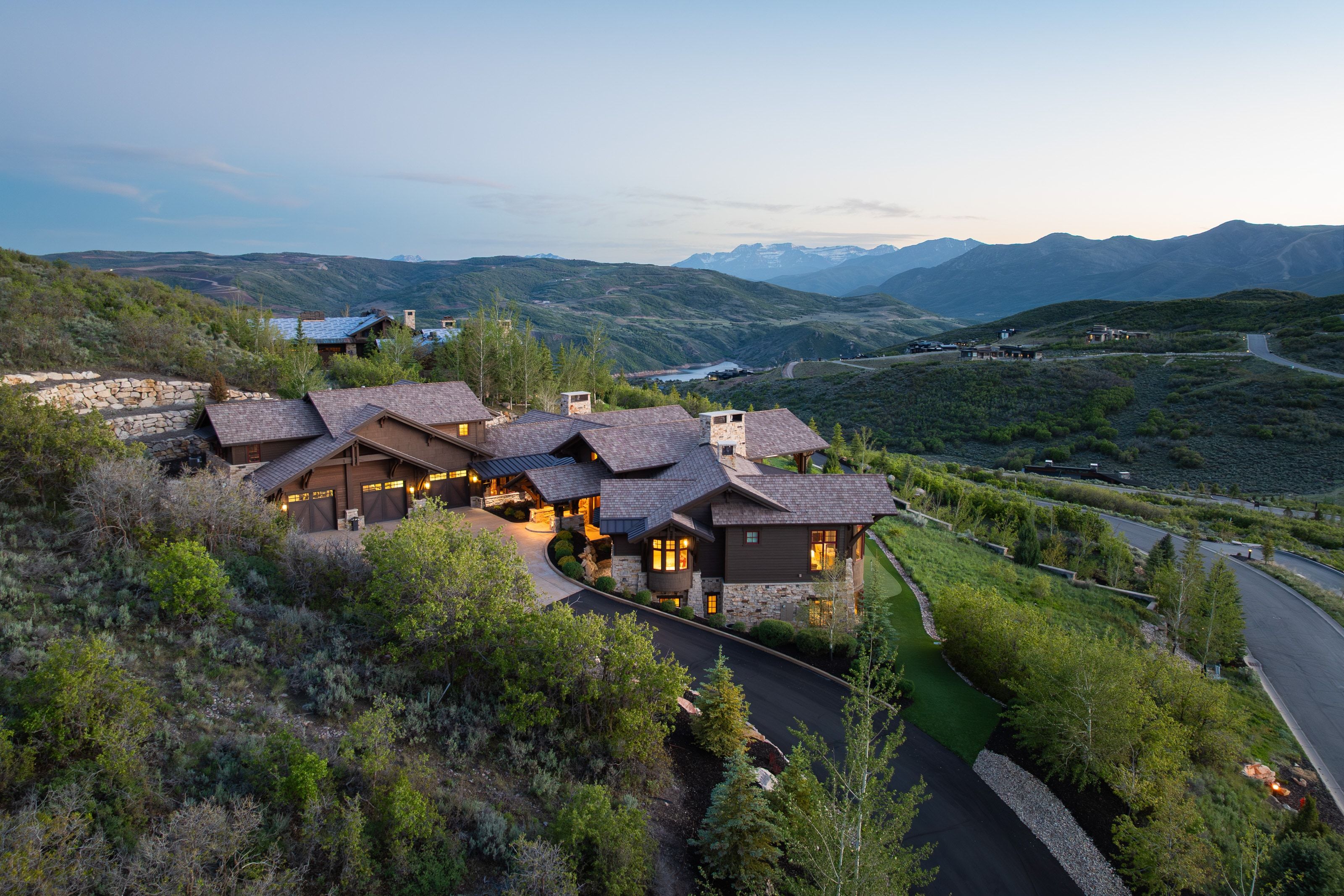 Expansive residence with multiple gabled roofs, stone and wood-finish siding, and a paved circular driveway