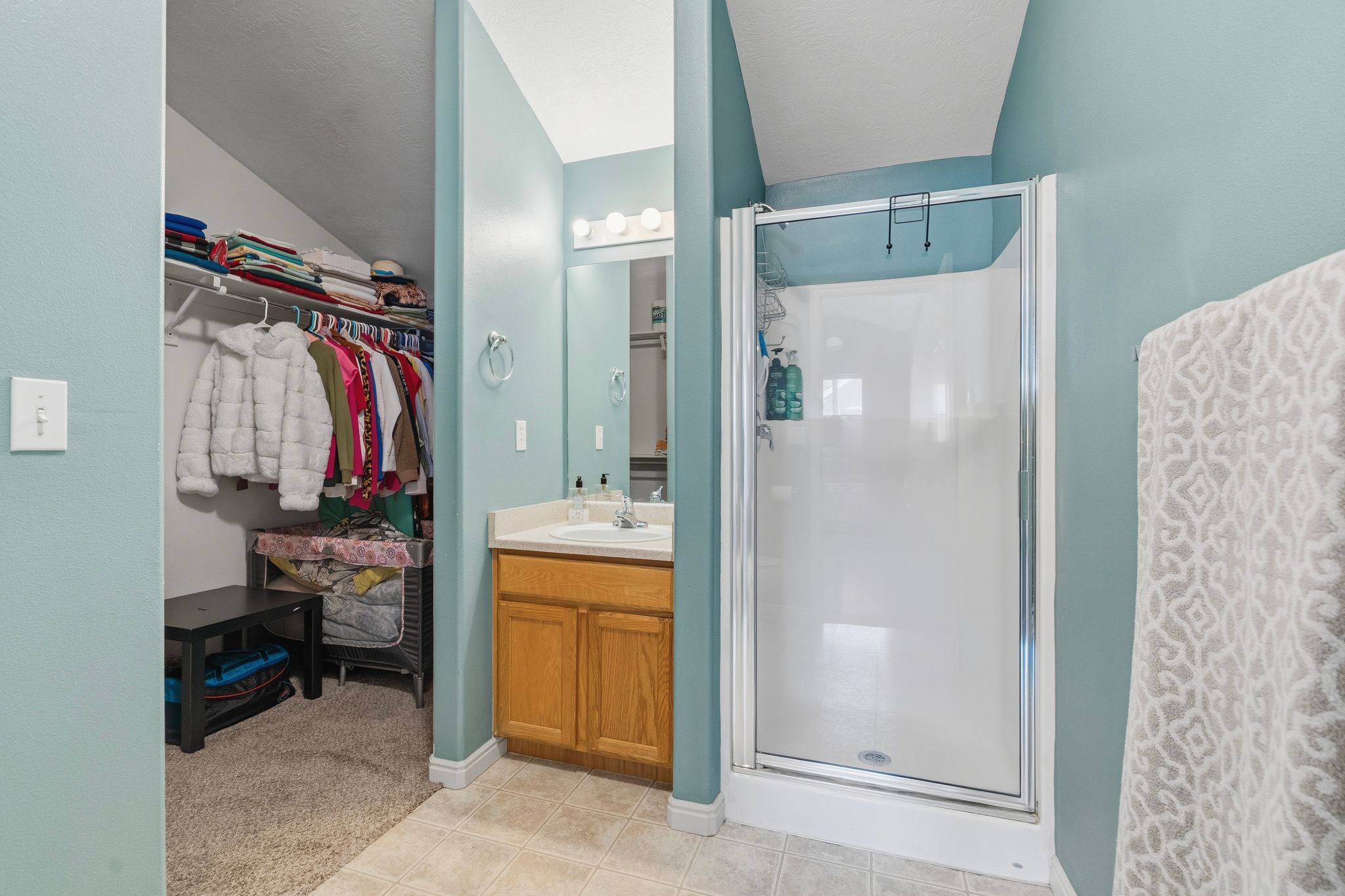 Bathroom with single vanity featuring a wood-finish cabinet and a shower enclosure with a glass door