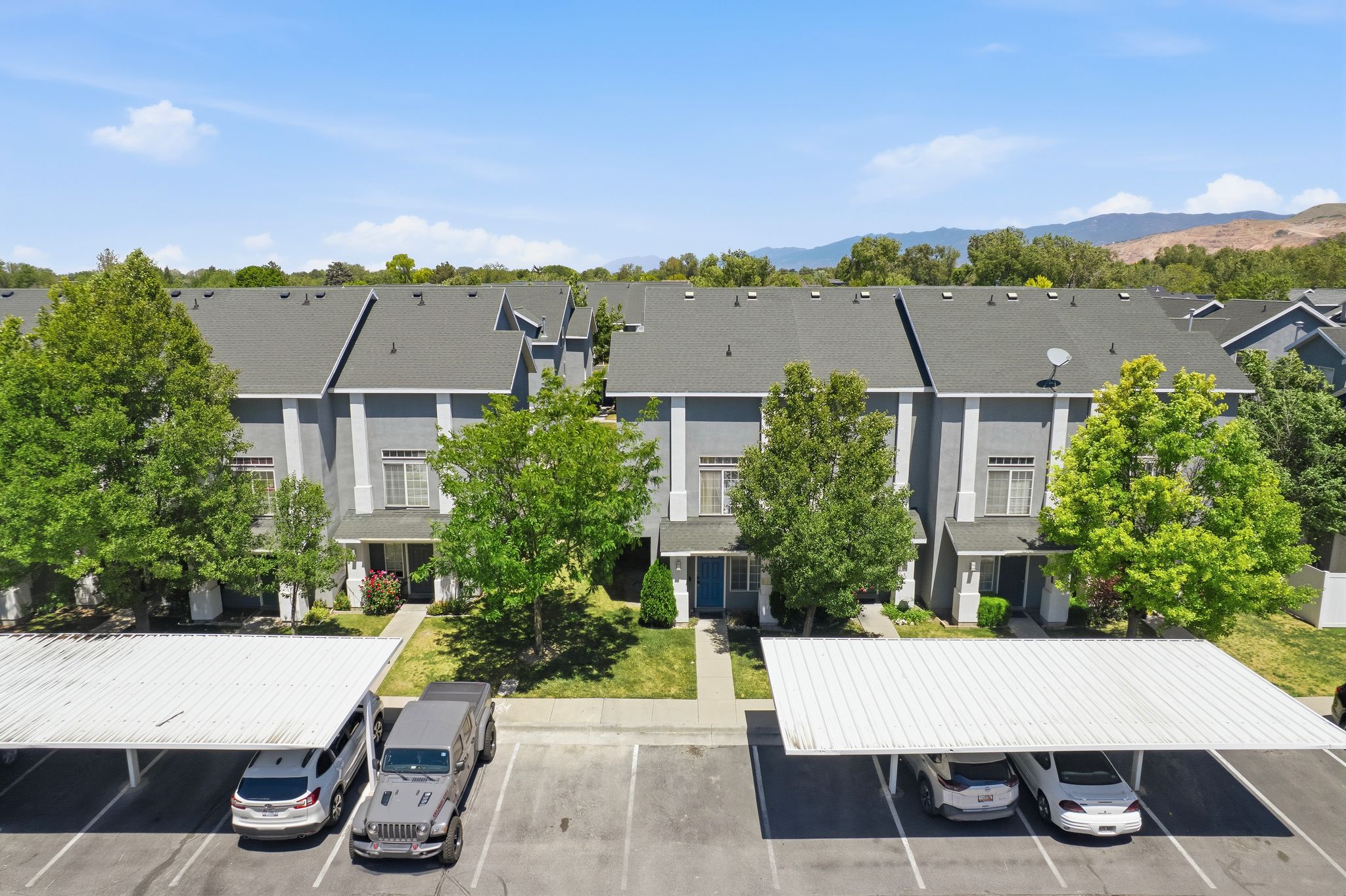 Townhome exterior featuring gray siding, white trim, and dark gray shingle roofing