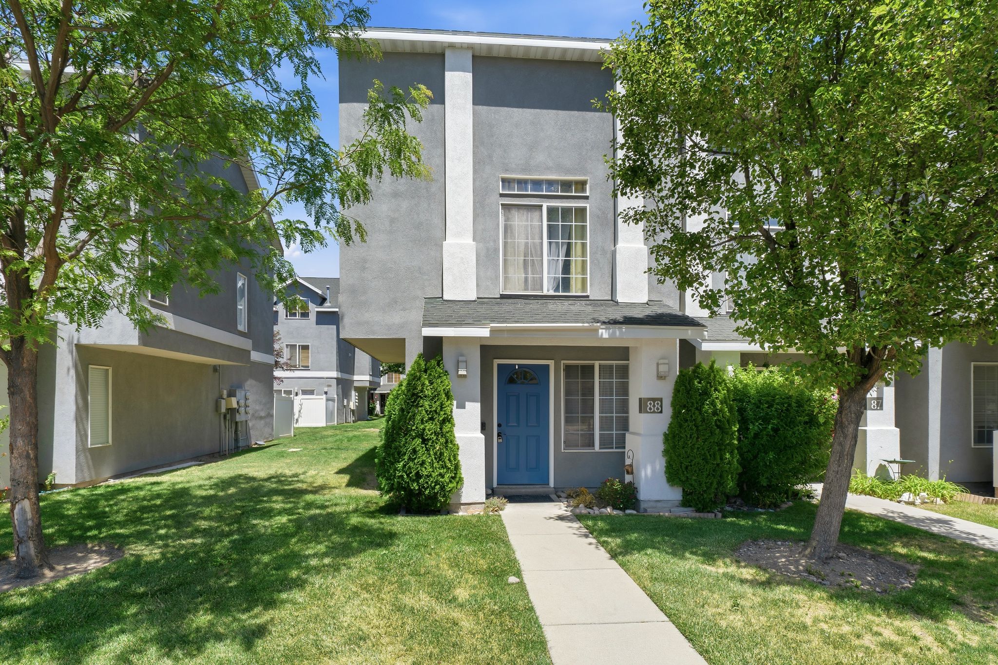 Two-story stucco exterior featuring a prominent blue entry door, an upper-level bay window, and a covered porch