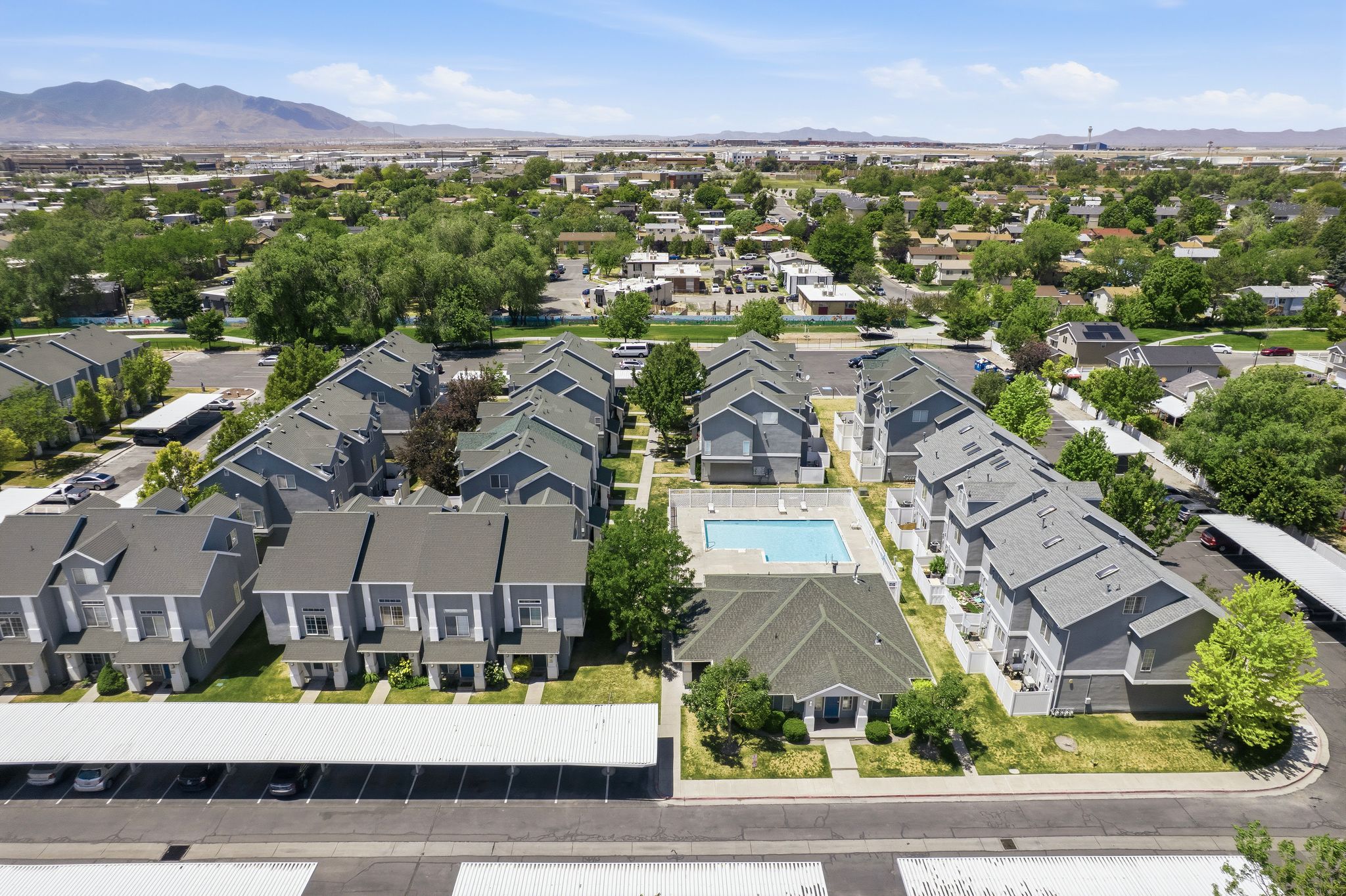 Aerial perspective showcasing a multi-building property featuring a central swimming pool and multiple carports
