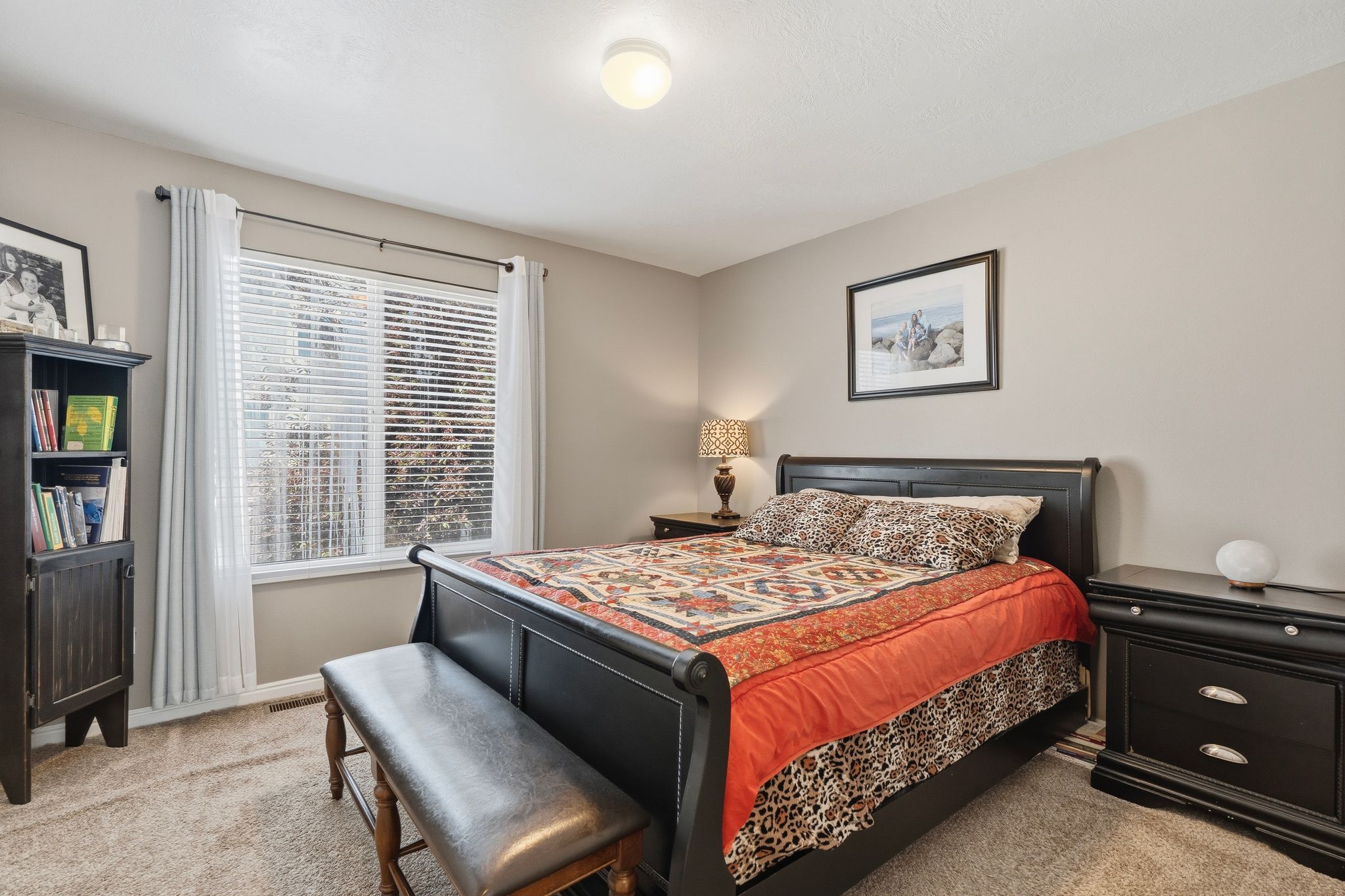 Carpeted room with a flush-mount ceiling light and a window with blinds and white curtains