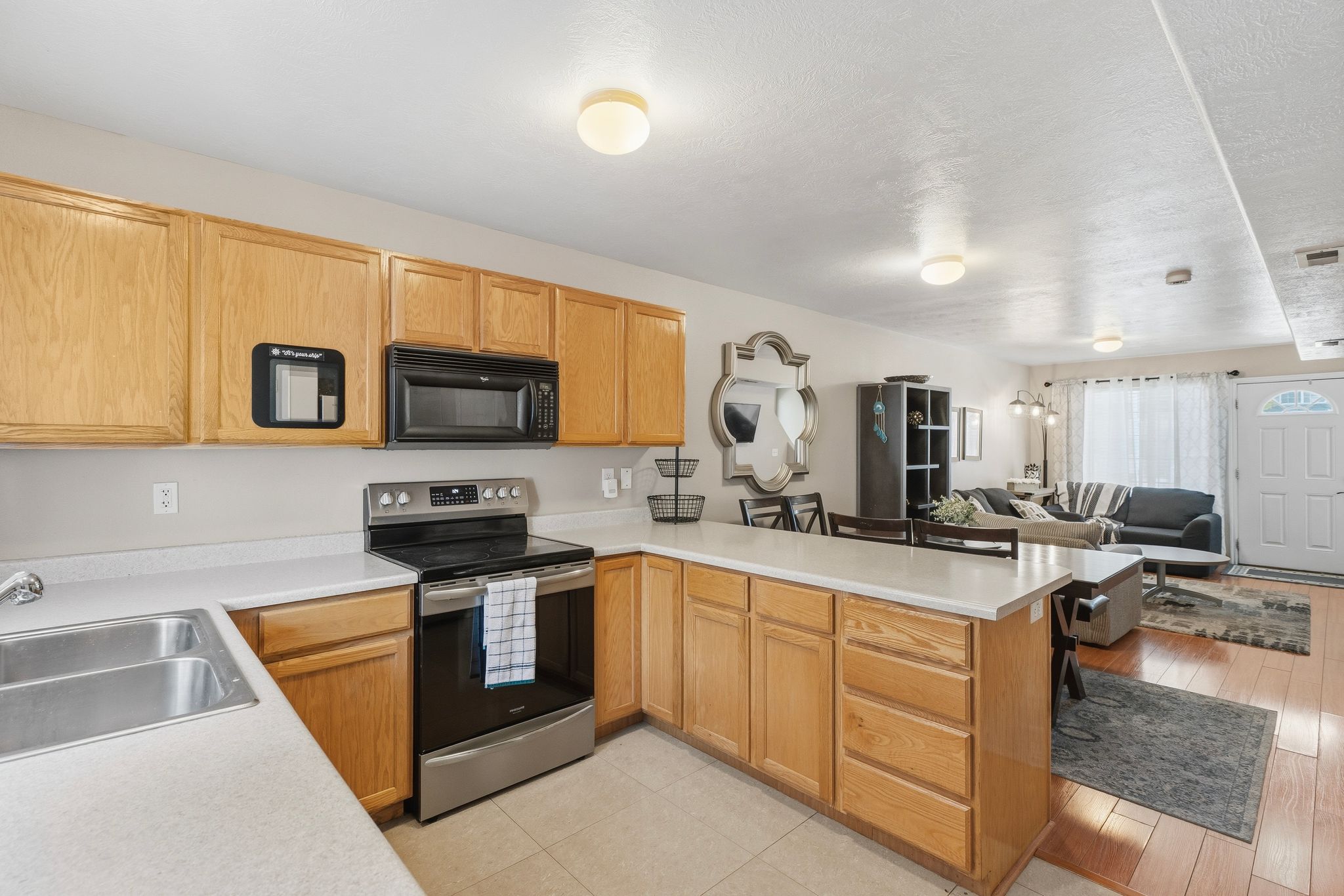 Kitchen featuring warm-toned cabinetry, light-colored countertops, a stainless steel electric range, and an over-range microwave