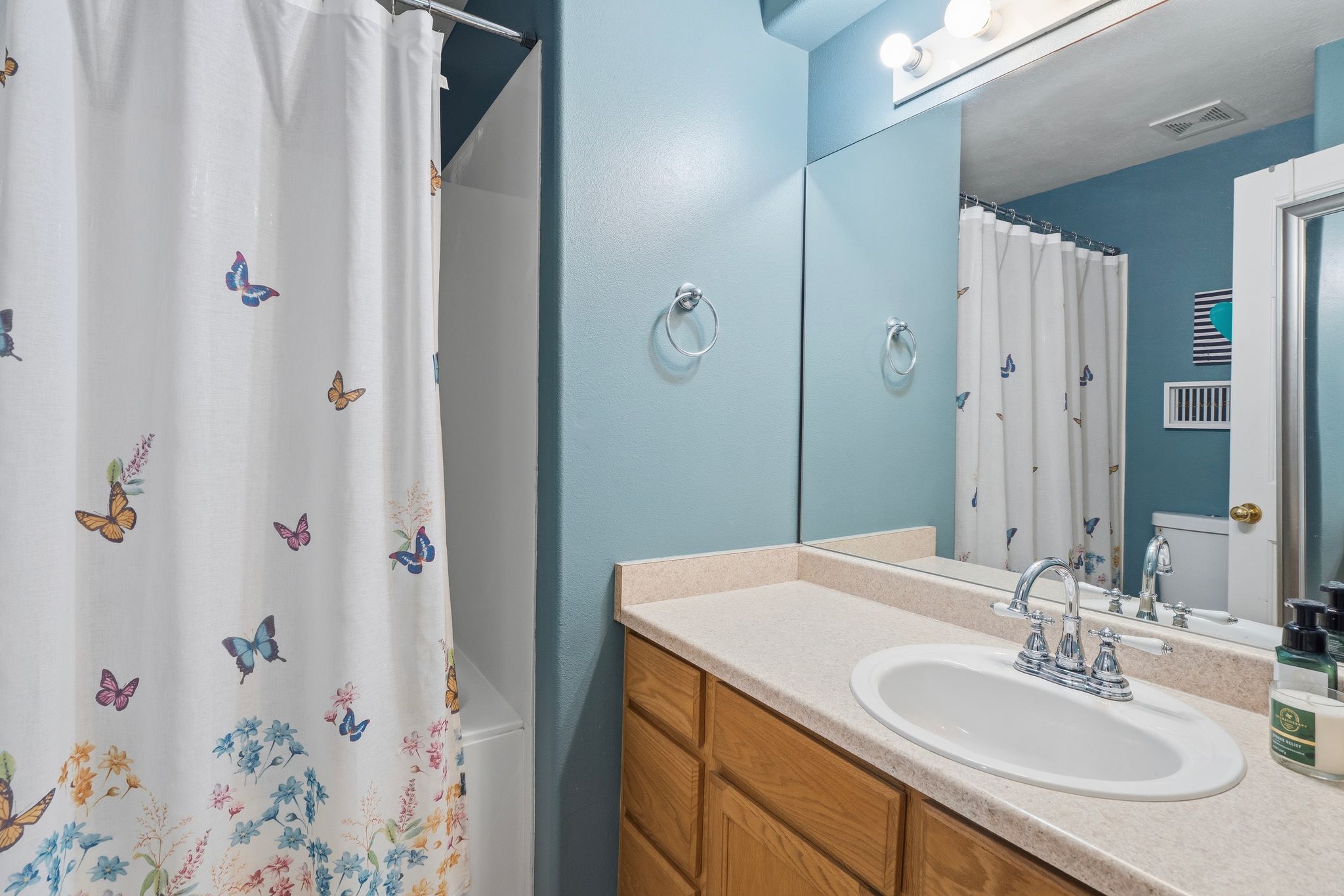 Bathroom vanity featuring a light-toned countertop with an integrated oval sink and chrome faucet