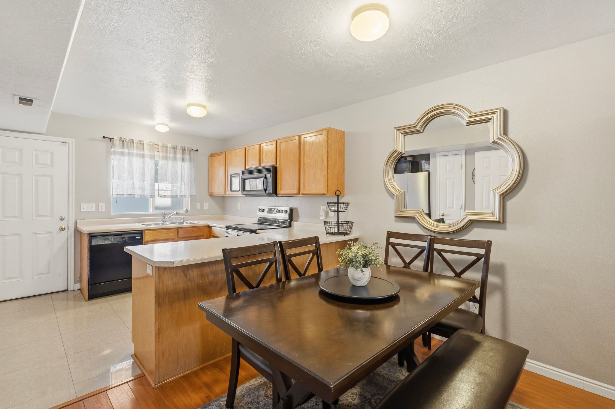 Open-concept kitchen and dining area featuring light wood cabinetry and black appliances