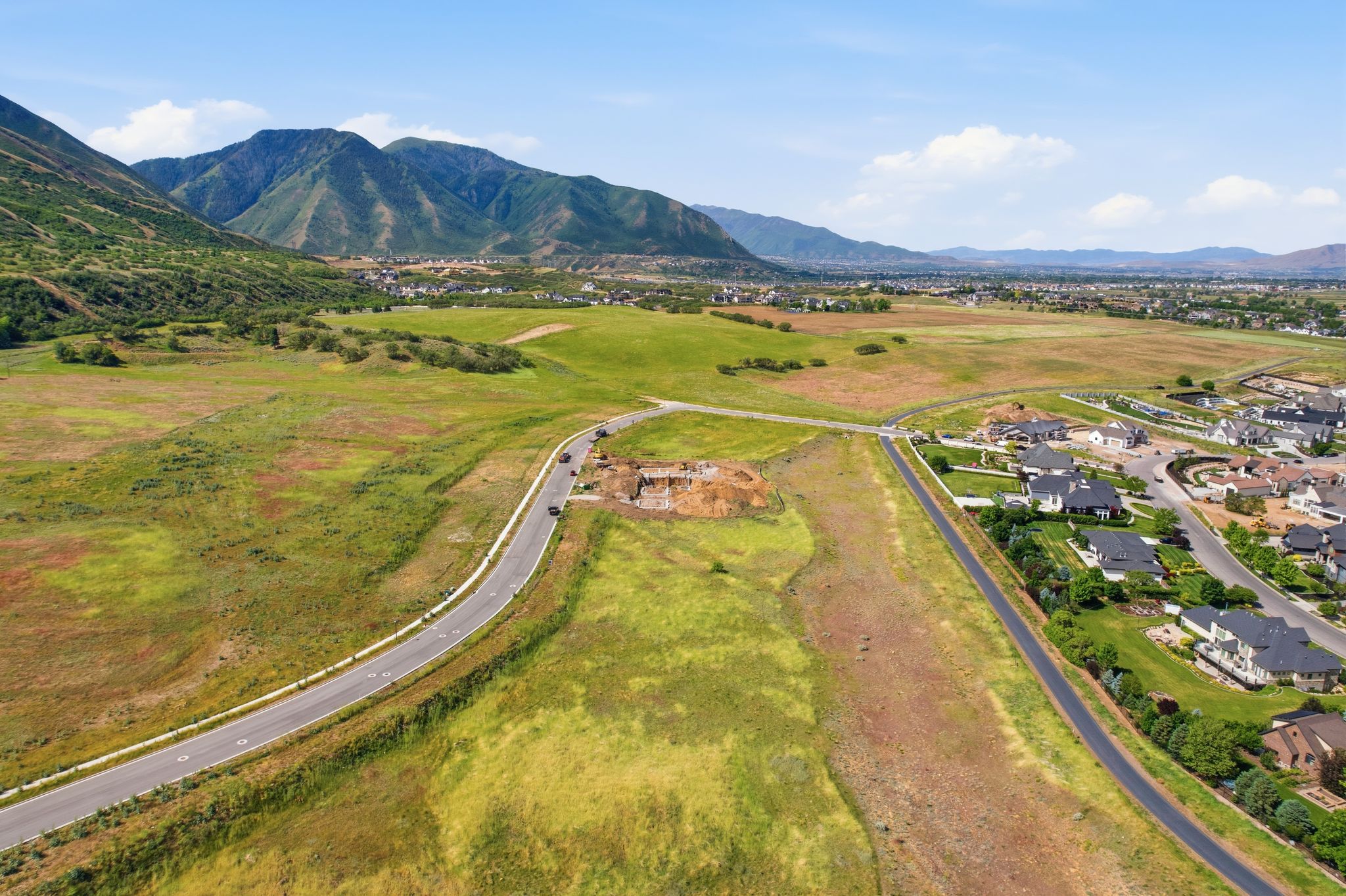 Expansive green landscape featuring a curved paved road and distant mountain range