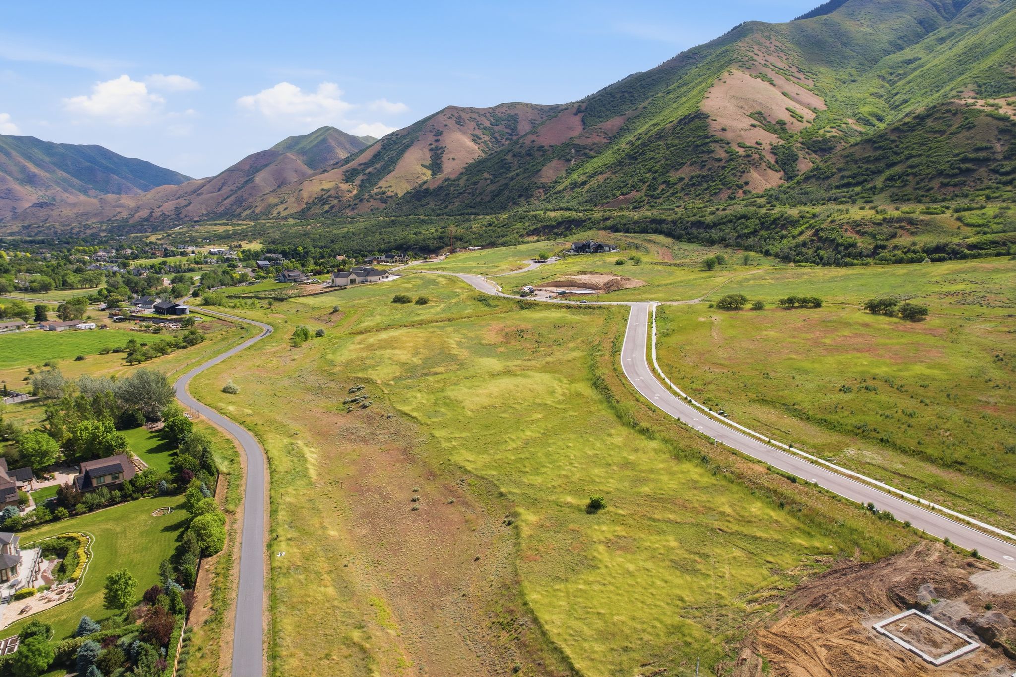 Expansive mountain landscape featuring rolling green hills and paved roadways