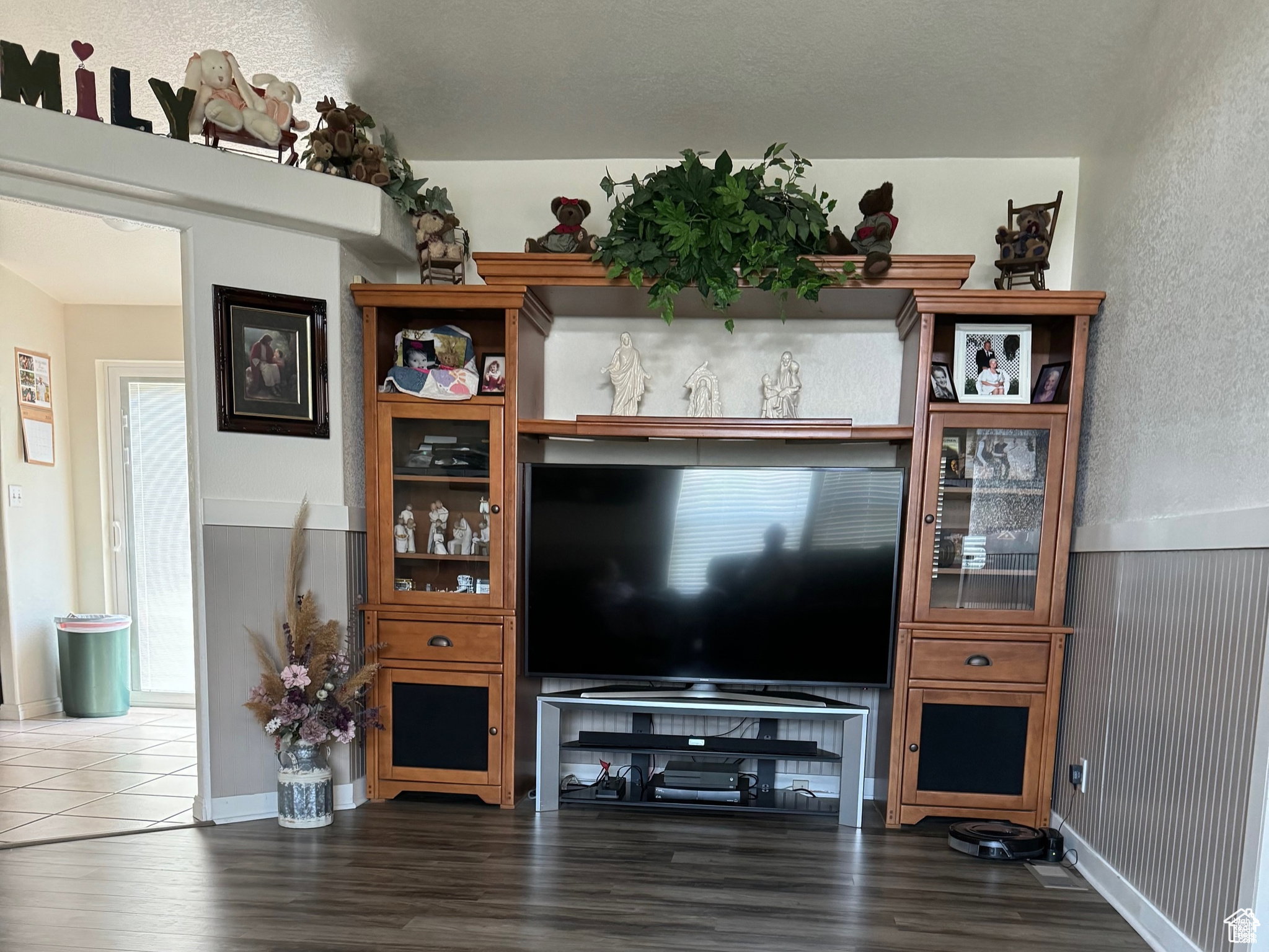 Living area featuring wood-finish flooring, wainscoting, and an open entryway