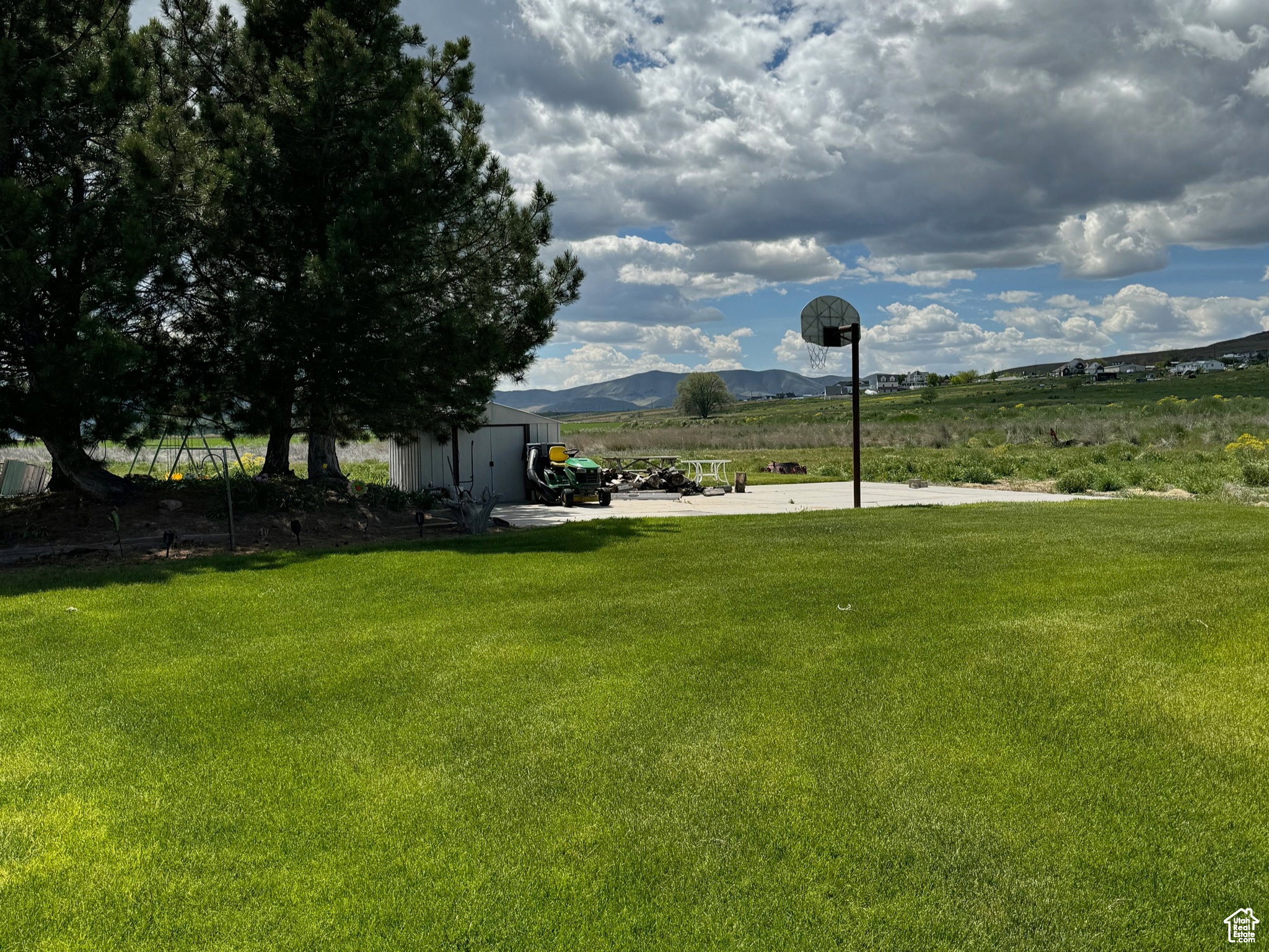 Expansive green lawn with a dedicated concrete court and basketball hoop