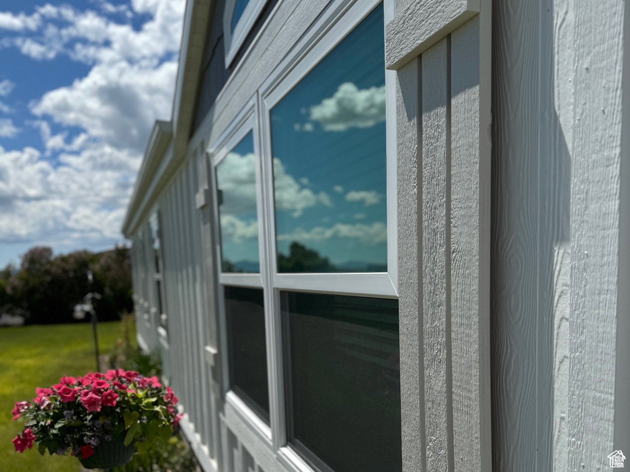 Exterior featuring white board-and-batten siding, horizontal siding, multiple windows, and a prominent gable