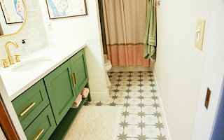 Bathroom featuring a green vanity with brass hardware, a white countertop, and an undermount sink with a brass faucet