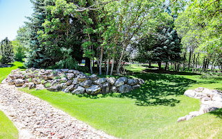 Lush green lawn with a decorative rock pathway and a natural rock retaining wall