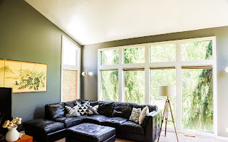 Vaulted ceiling living space featuring a large picture window, additional transom windows, sconce lighting, and wood-finish flooring