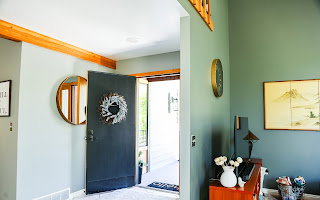 Entryway featuring a dark paneled door, wood-finish trim, and a circular wall mirror