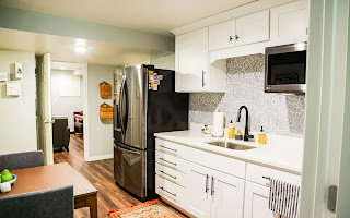 Well-appointed kitchen featuring white cabinetry, light-toned countertops, a patterned tile backsplash, and wood-finish flooring