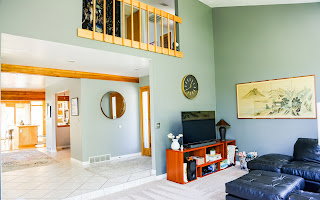 Vaulted ceiling living area featuring a loft overlook with wood railing