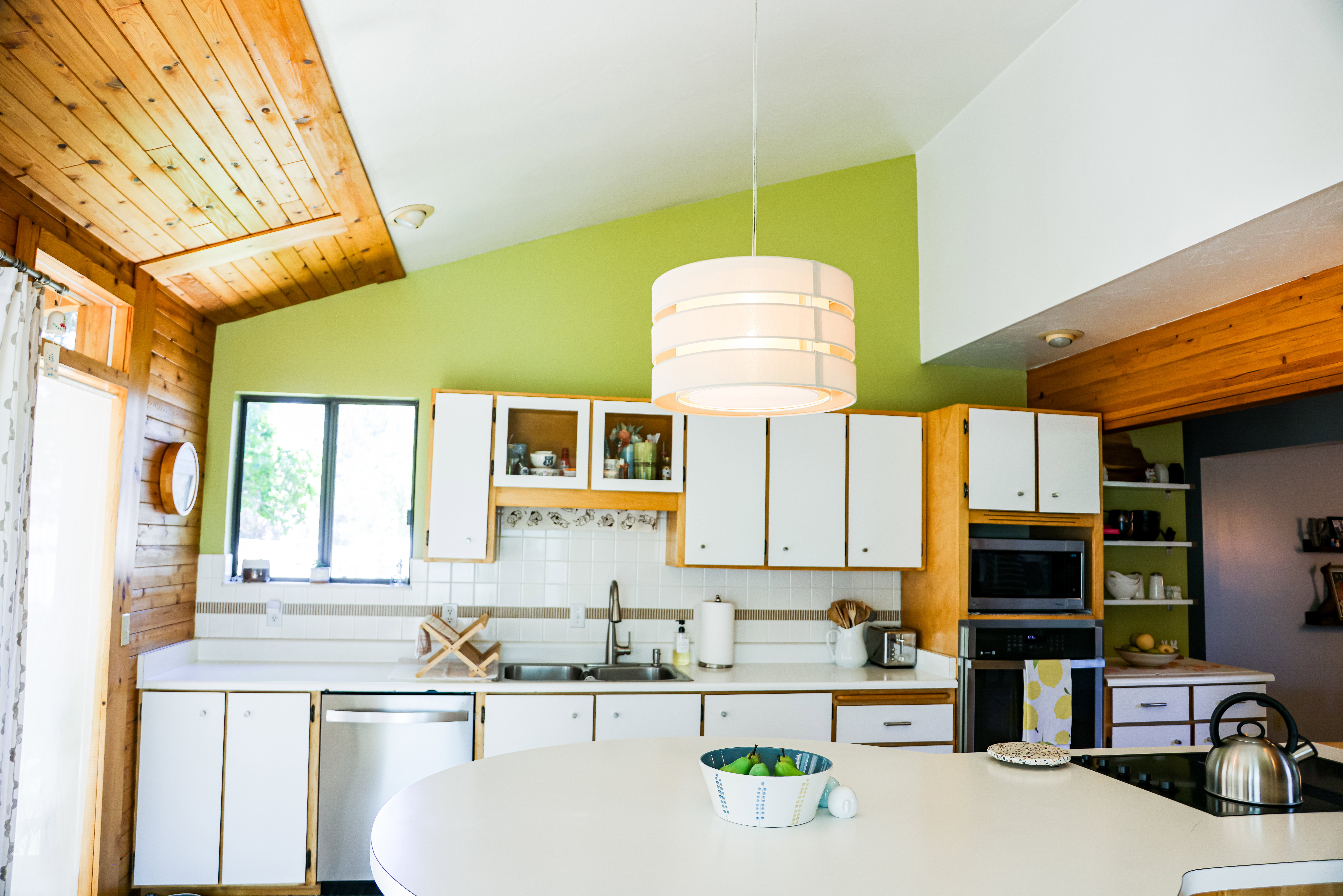 Kitchen featuring a vaulted wood-paneled ceiling, white cabinetry, integrated appliances, and a central island with a cooktop