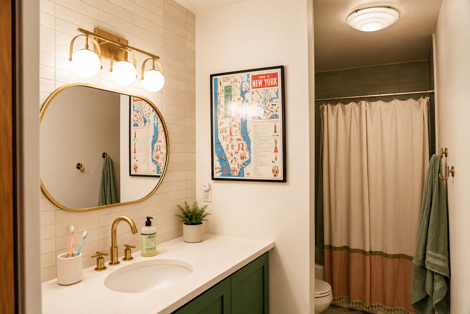 Bathroom featuring a white countertop with an undermount sink and brass-finish faucet, dark green cabinetry, and an oval mirror with a brass-finish frame
