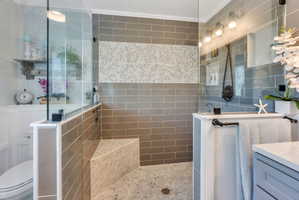 Walk-in shower featuring glass enclosure, subway tile walls, pebble tile flooring, and an integrated pebble tile bench
