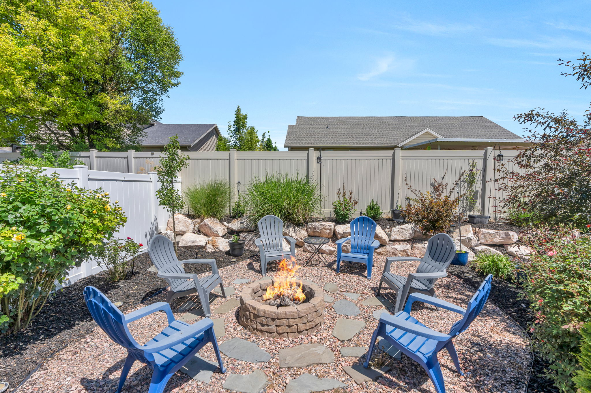 Outdoor fire pit area with a stone-finish fire pit, surrounded by decorative stone pavers and bark mulch