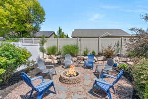 Outdoor fire pit area with a stone-finish fire pit, surrounded by decorative stone pavers and bark mulch