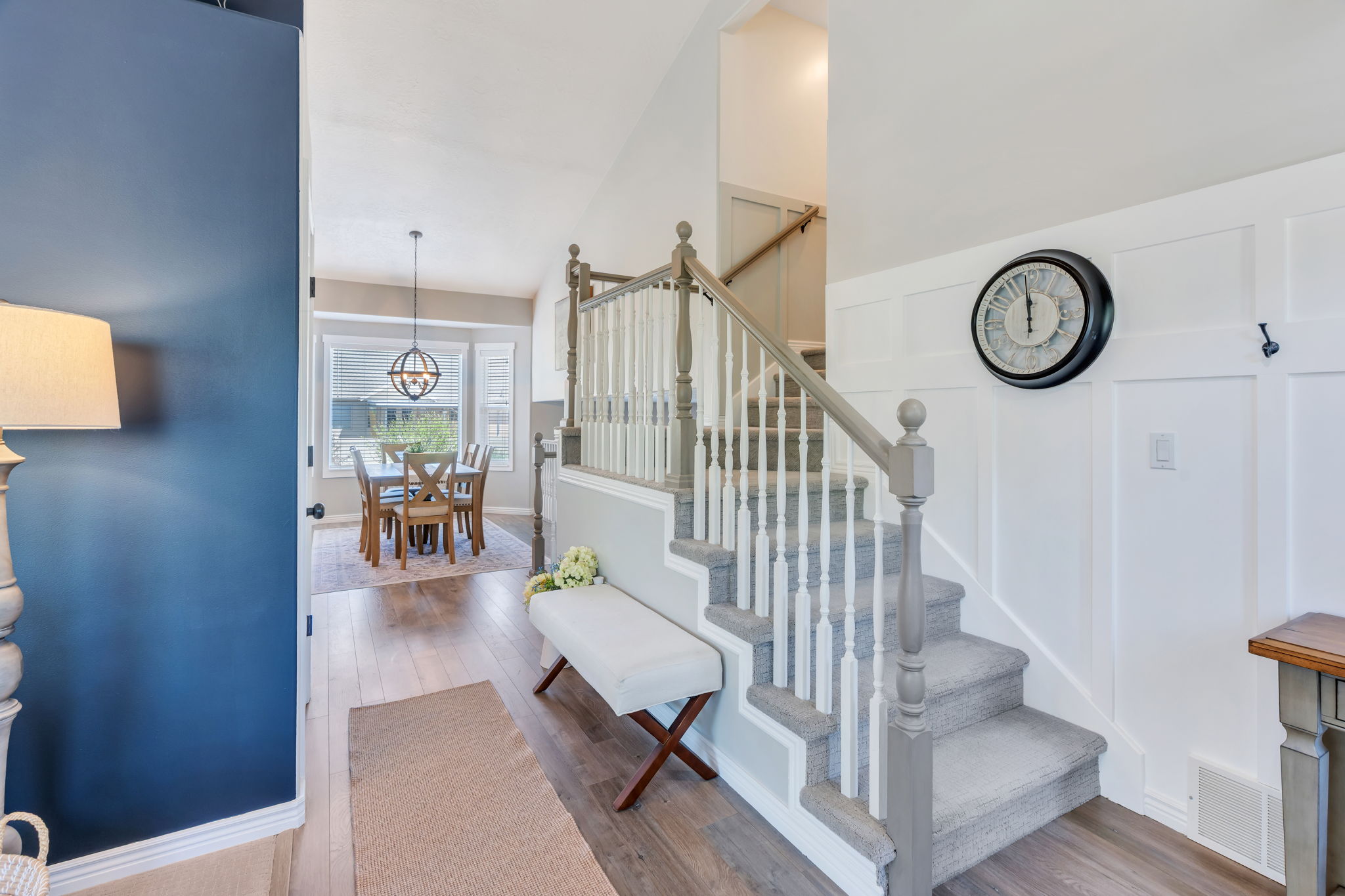 Foyer featuring a carpeted staircase with painted wood railings, a board and batten accent wall, and wood-finish flooring