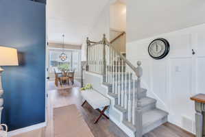 Foyer featuring a carpeted staircase with painted wood railings, a board and batten accent wall, and wood-finish flooring