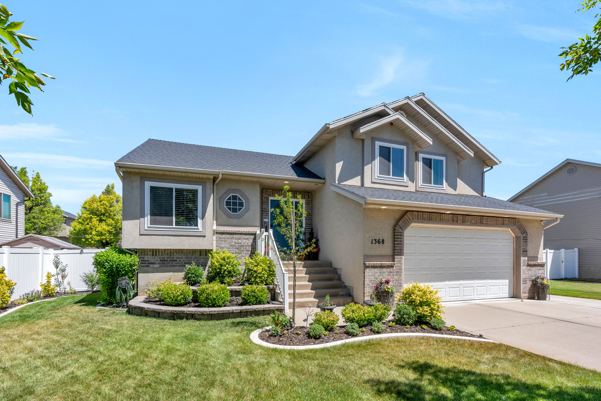 Stucco and brick exterior with a two-car garage, established front landscaping, and a manicured lawn