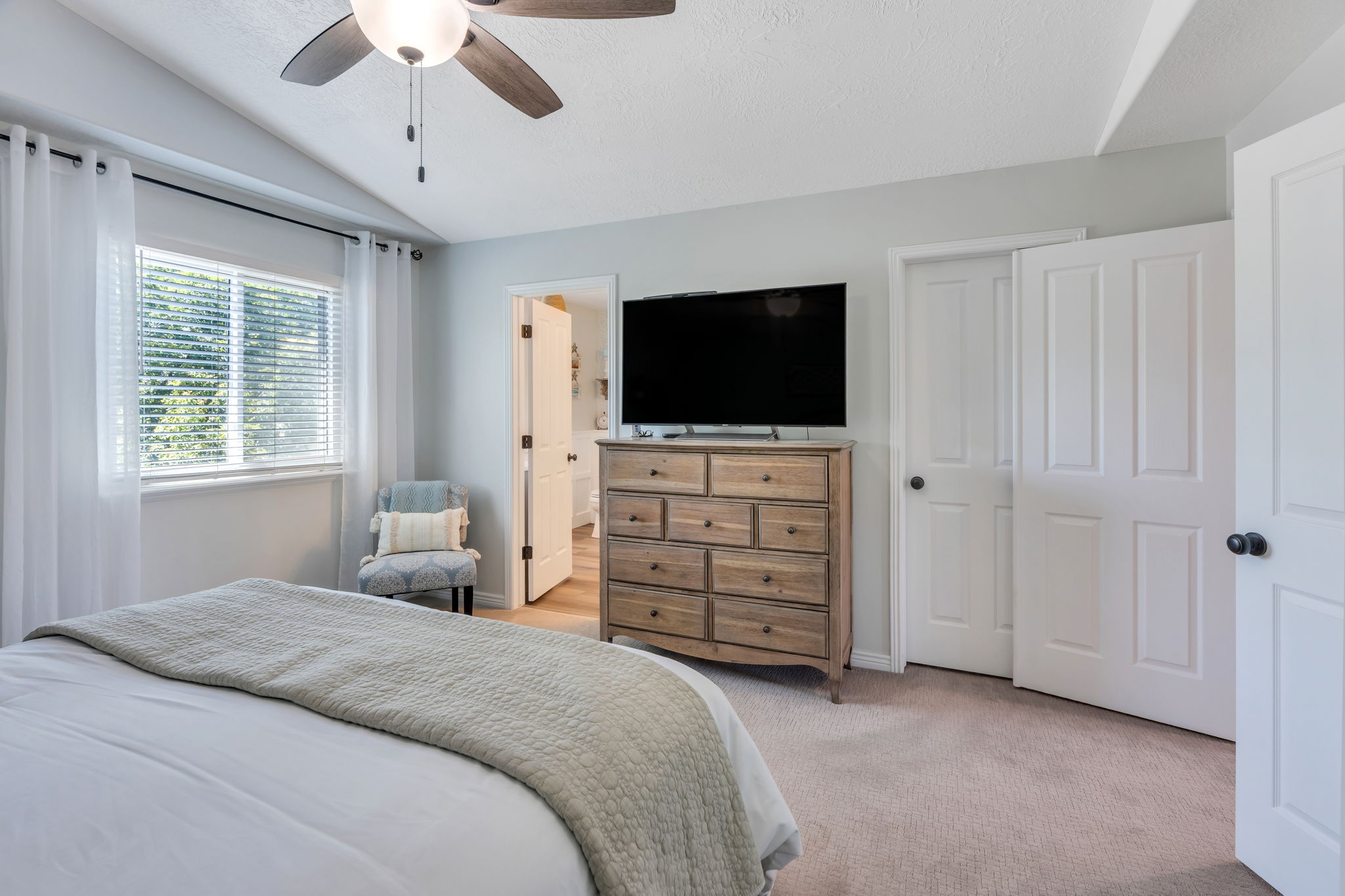 Bedroom featuring a vaulted ceiling with a ceiling fan, a window with blinds, and light-colored carpeting