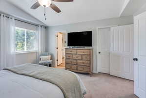 Bedroom featuring a vaulted ceiling with a ceiling fan, a window with blinds, and light-colored carpeting
