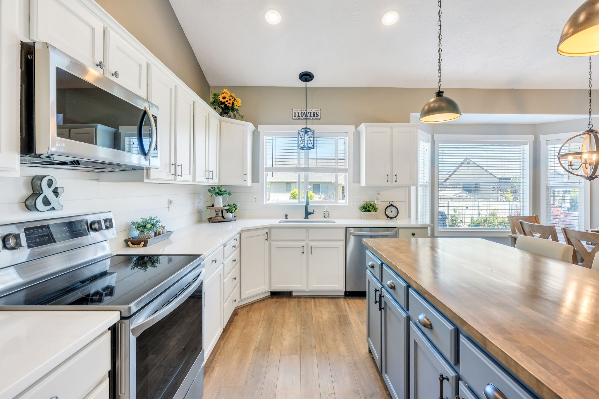 Contemporary kitchen featuring white cabinetry, stainless steel appliances, light wood-finish flooring, a butcher block island, and recessed lighting